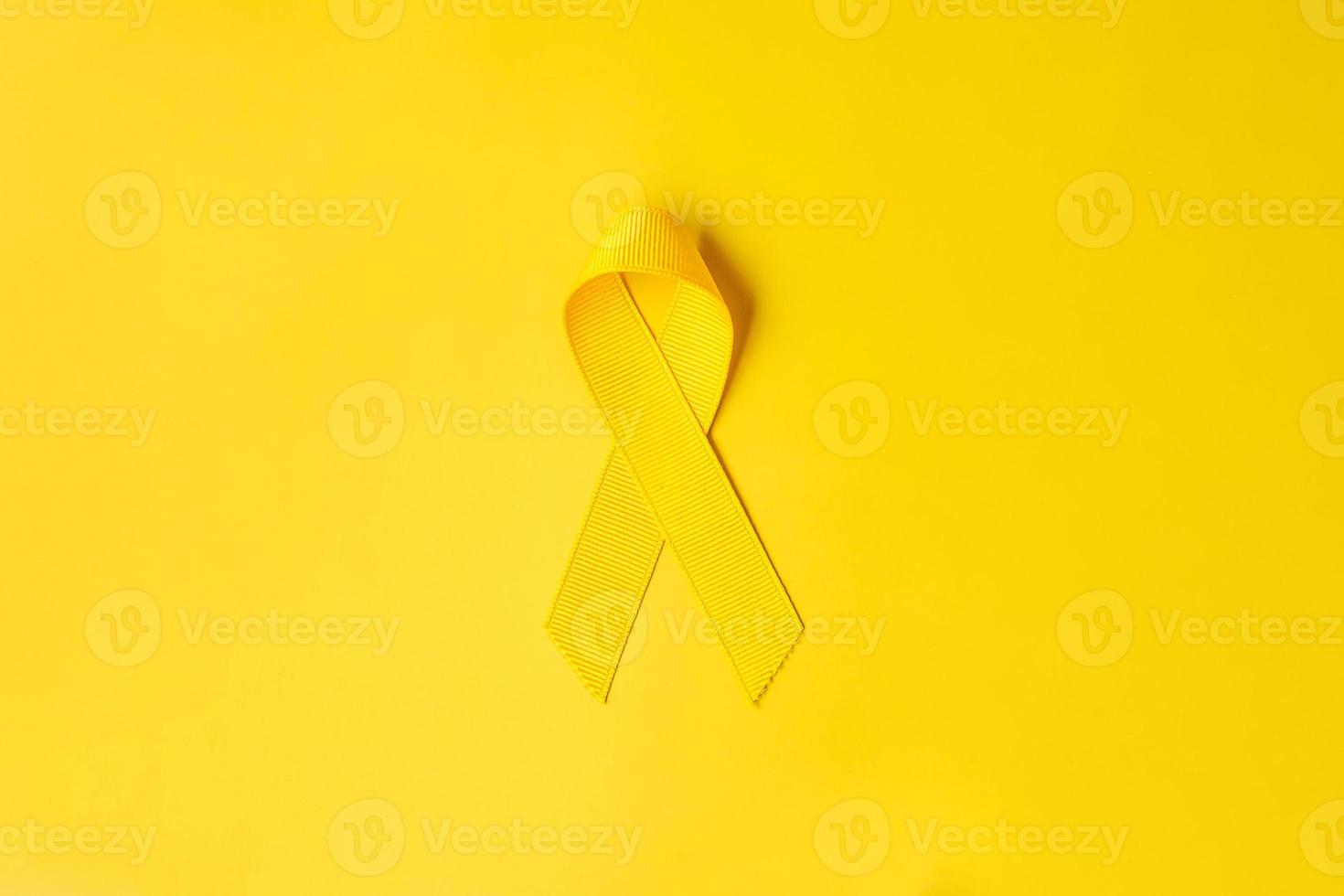 ruban jaune sur fond jaune pour soutenir les personnes vivant et malades. journée de prévention du suicide en septembre, mois de sensibilisation au cancer infantile et concept de journée mondiale contre le cancer photo