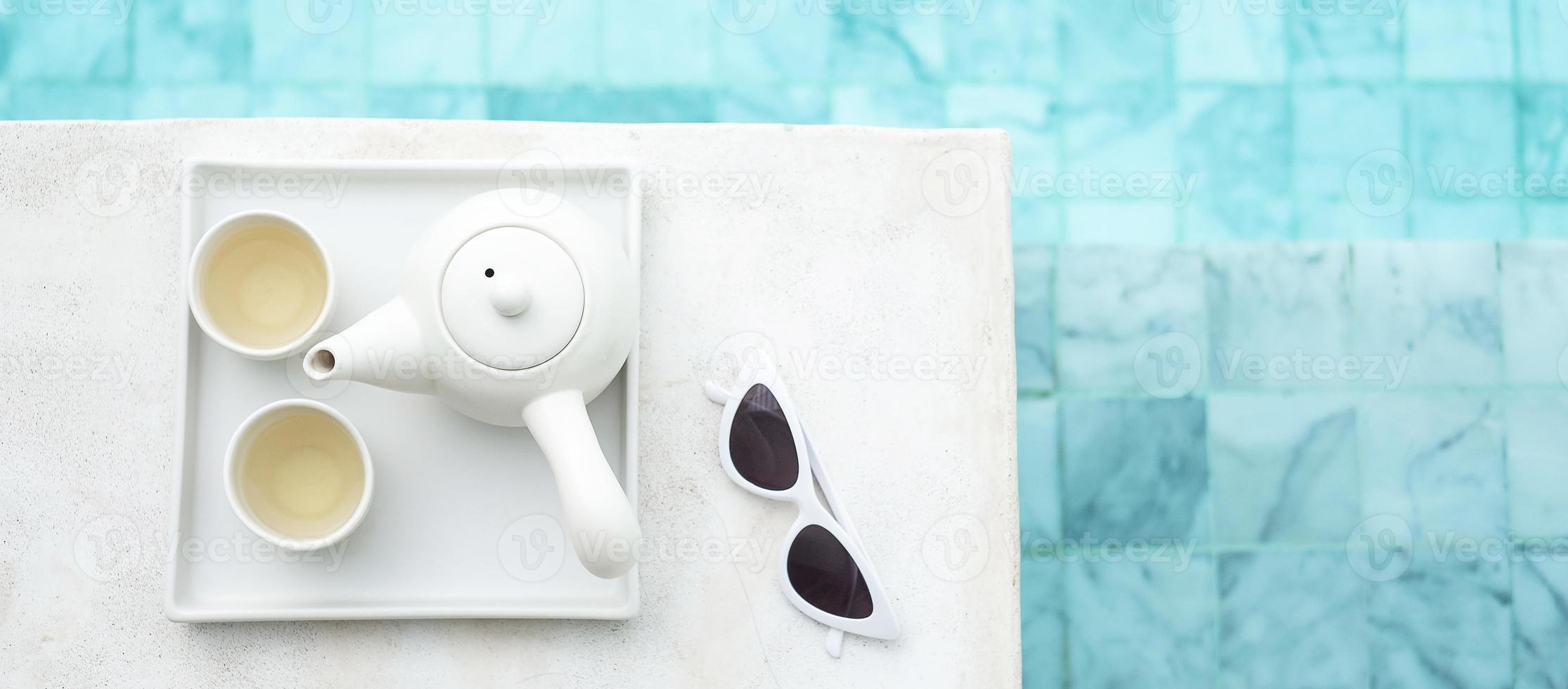lunettes de soleil blanches et théière chaude près de la piscine dans un hôtel de luxe. voyage d'été, vacances, vacances et concept de week-end photo