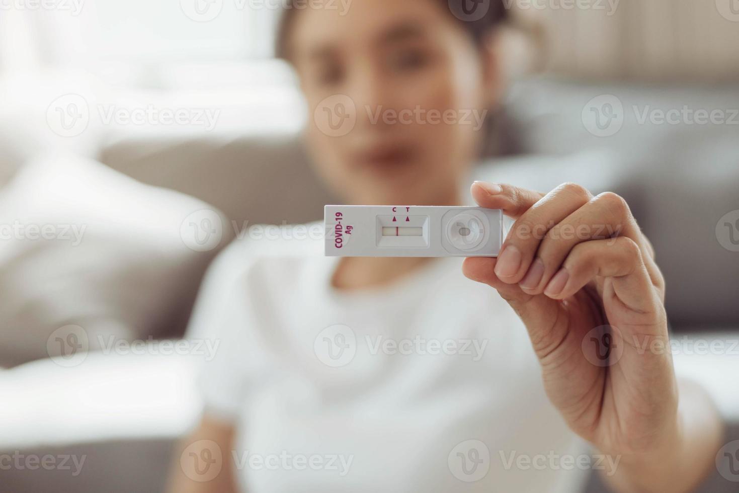 autotest femme pour le kit de test à domicile covid-19. femme asiatique montrant le résultat kit de test à domicile d'antigène rapide de coronavirus, test d'écouvillonnage nasal de coronavirus pour l'infection. photo