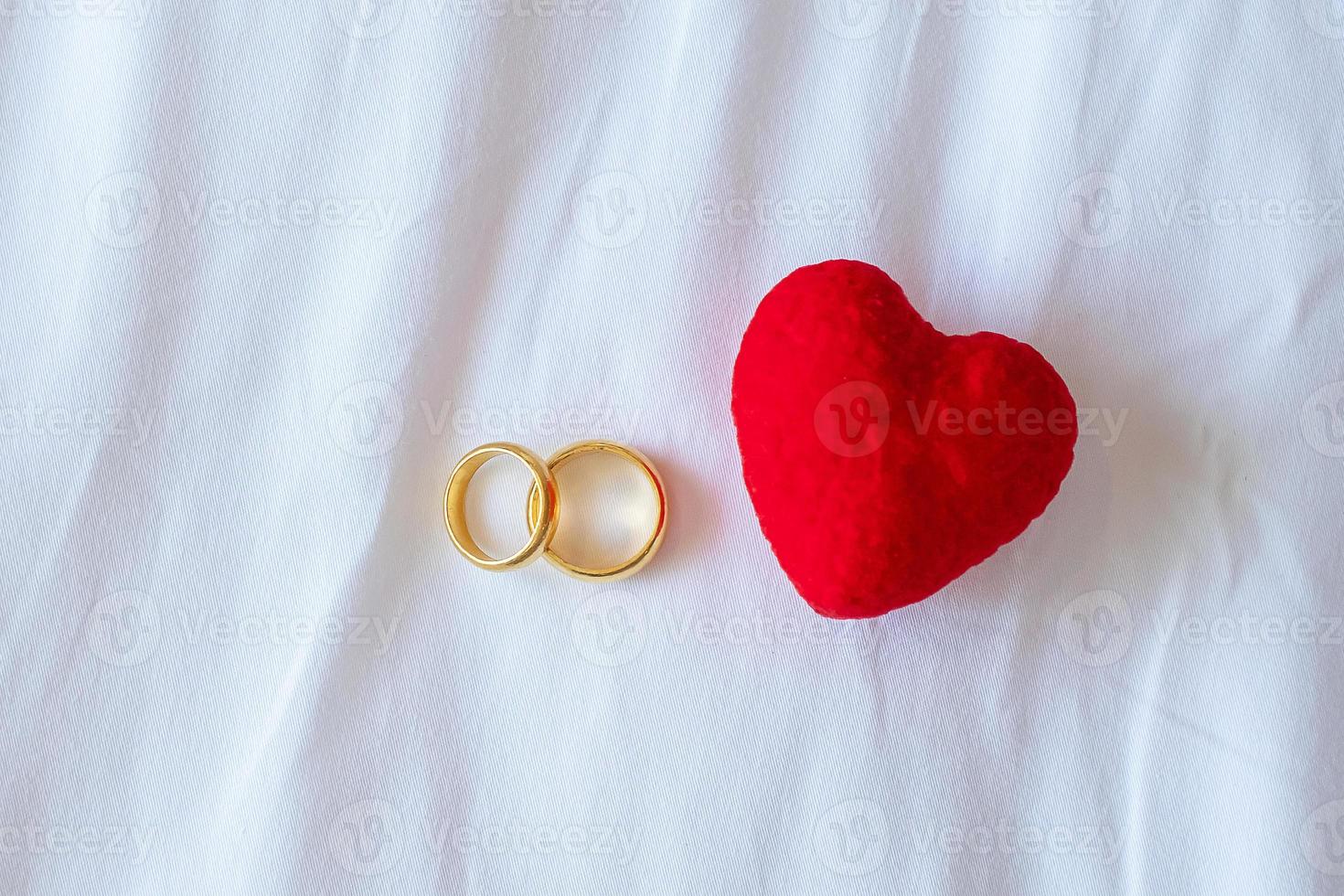 décoration en forme de coeur et bague de fiançailles dorée couple sur fond blanc. concept d'amour, ensemble et bonne saint valentin photo