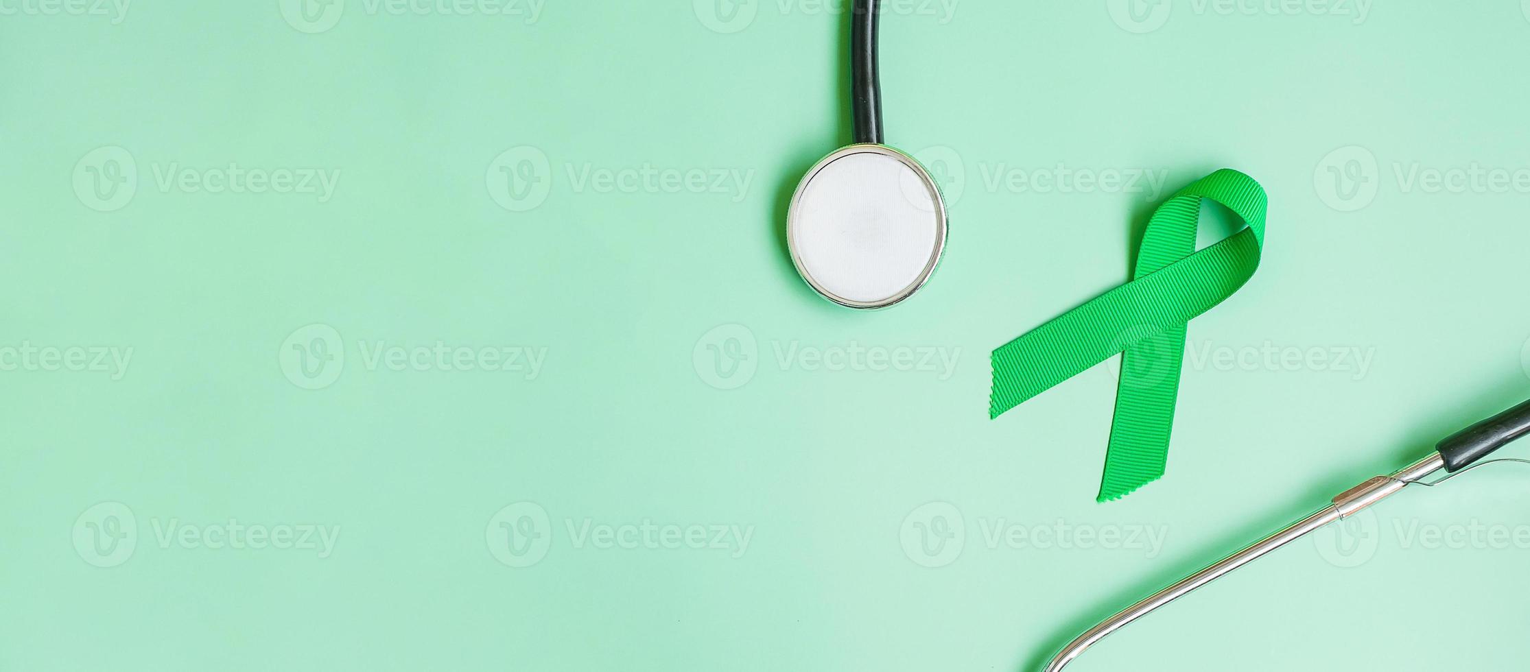ruban vert avec stéthoscope sur fond de couleur verte pour soutenir les personnes vivant et malades. foie, vésicule biliaire cancer des voies biliaires et concept de mois de sensibilisation au don d'organes photo