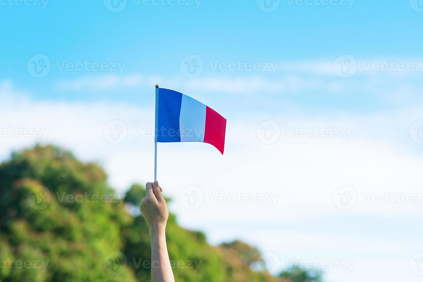 main tenant le drapeau de la france sur fond de ciel bleu. vacances de la fête nationale française, du jour de la bastille et des concepts de célébration heureuse photo