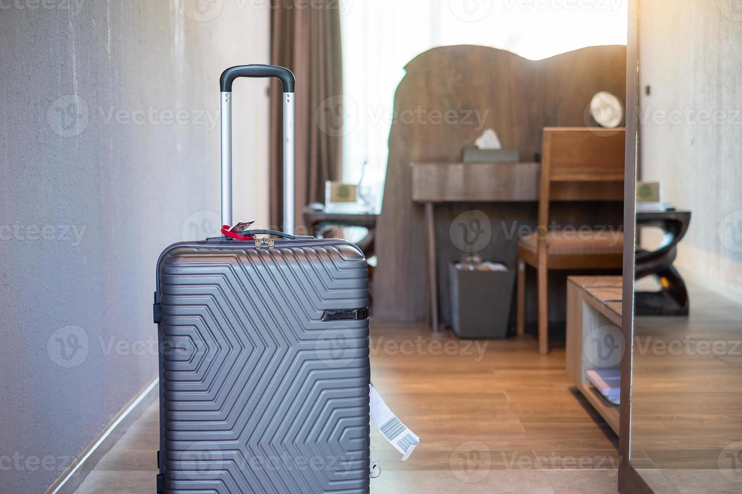 bagages gris dans une chambre d'hôtel moderne avec fenêtres, rideaux et lit. le temps de voyager, de détente, de voyage, de voyages et de concepts de vacances photo