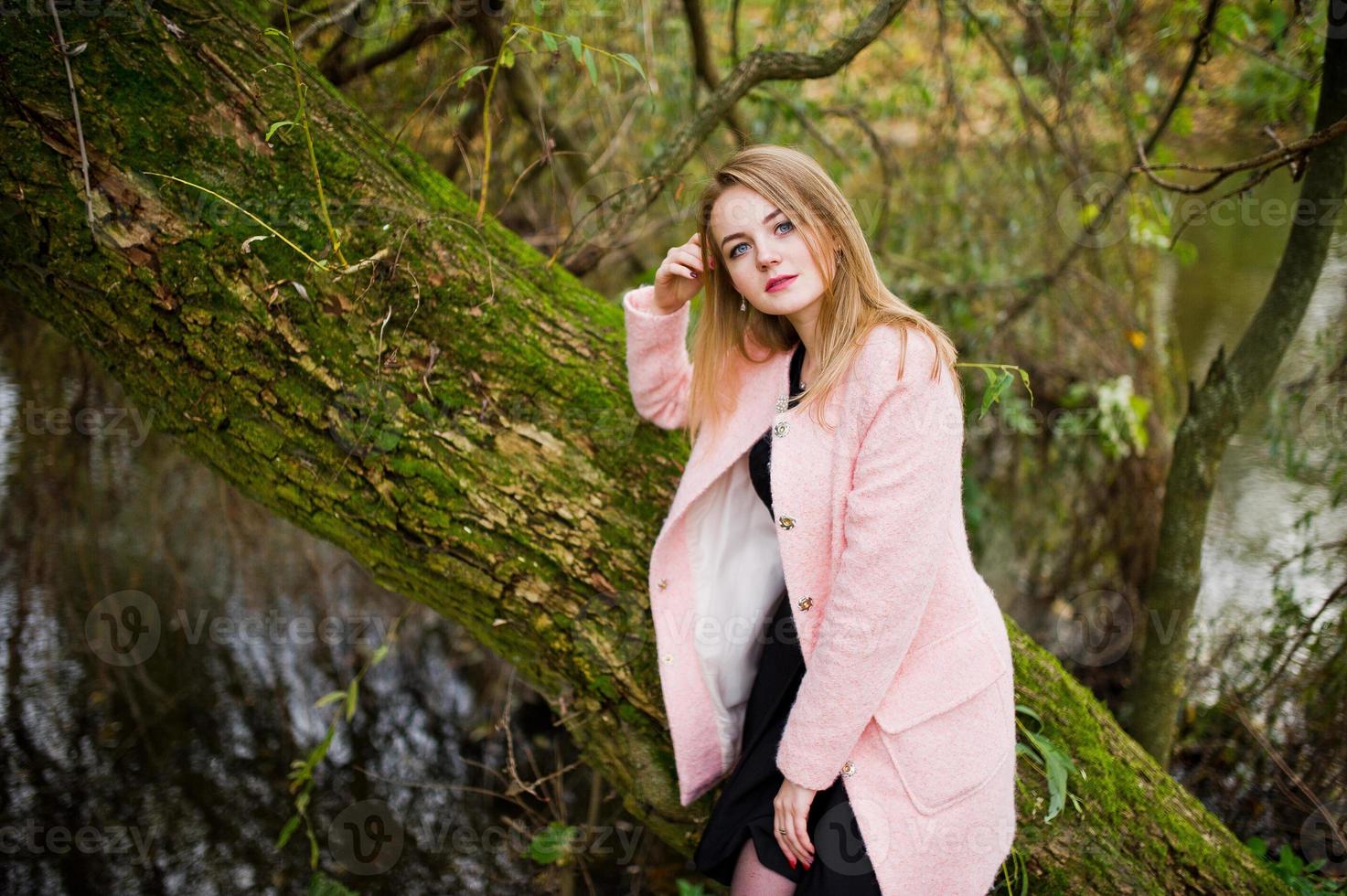 jeune fille blonde au manteau rose posé sur le parc d'automne. photo