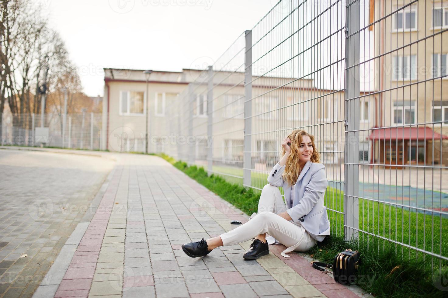 fille modèle blonde bouclée élégante porter sur blanc posant contre la clôture. photo