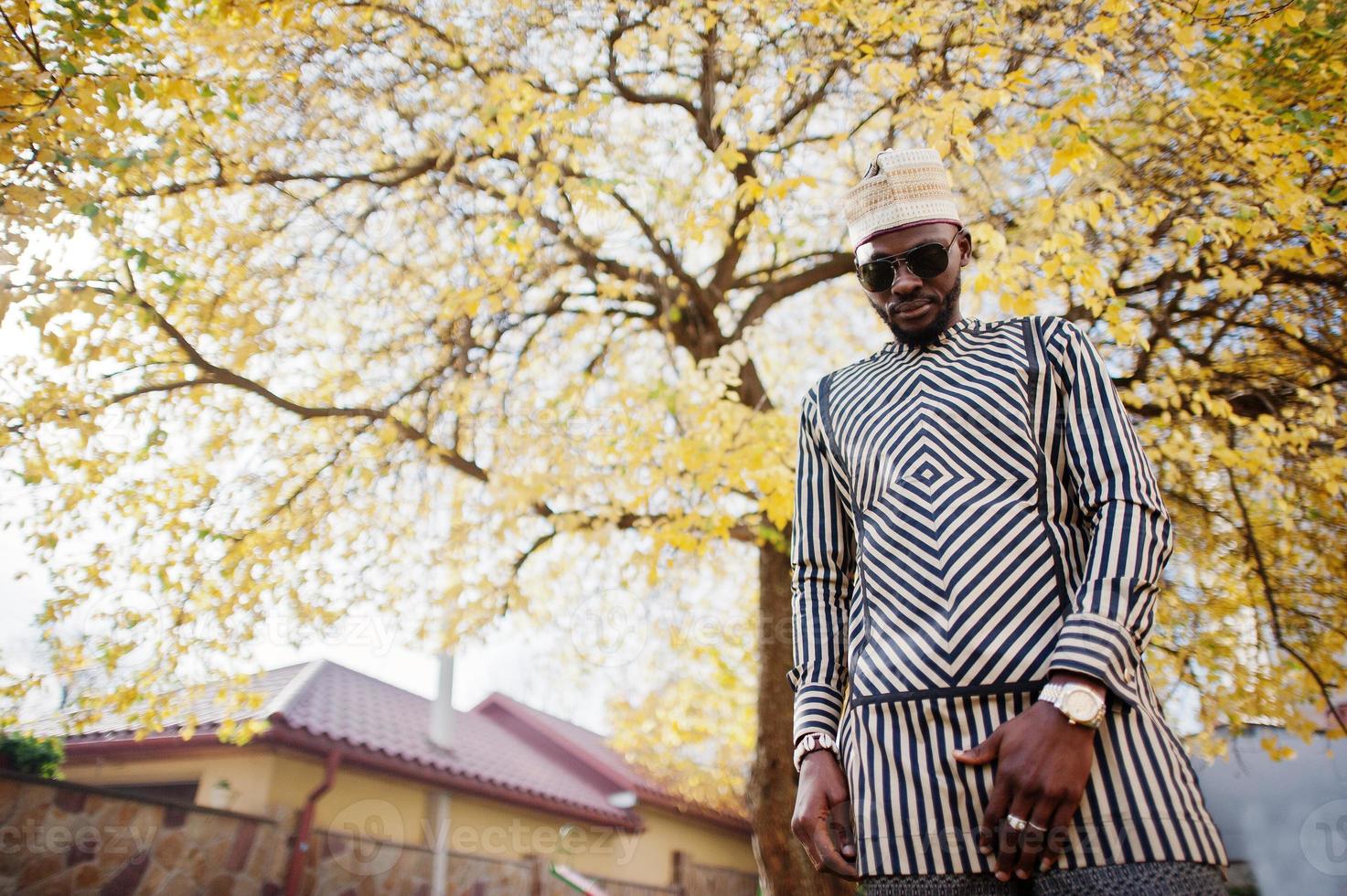 portrait d'un homme afro-américain noir élégant au chapeau et lunettes de soleil sur fond d'automne automne ensoleillé. les riches en afrique en costume traditionnel. photo