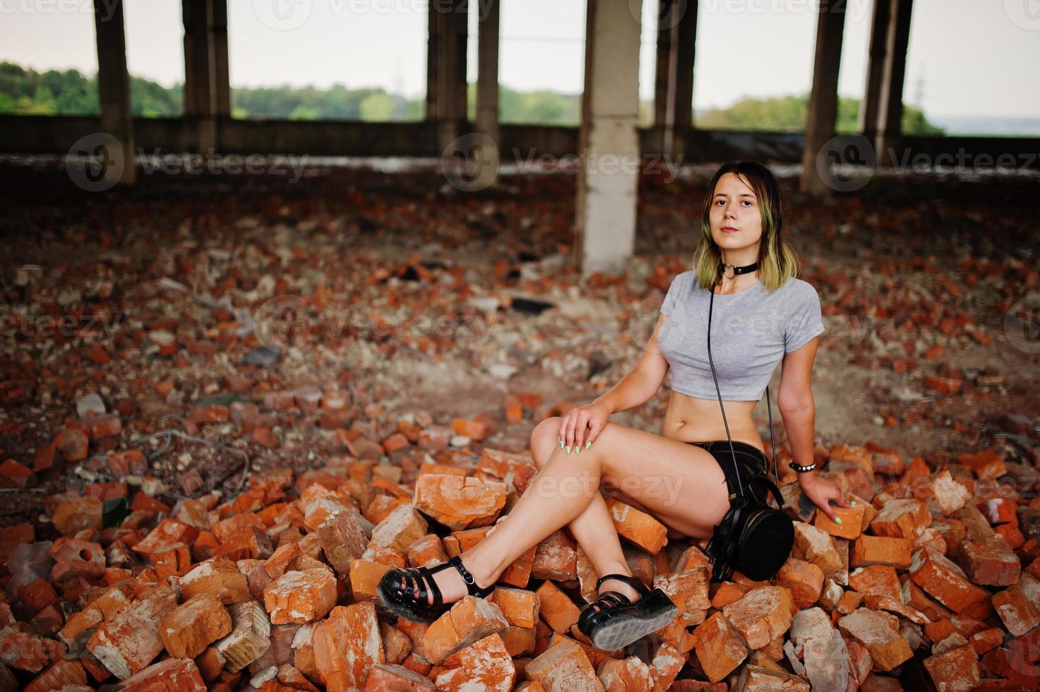 vêtements de fille sur des shorts à une usine abandonnée assise sur de la brique. photo