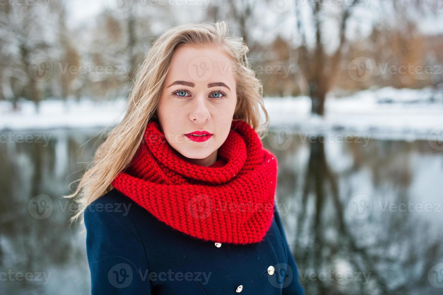 portrai de fille blonde en écharpe rouge et manteau contre lac gelé le jour de l'hiver. photo