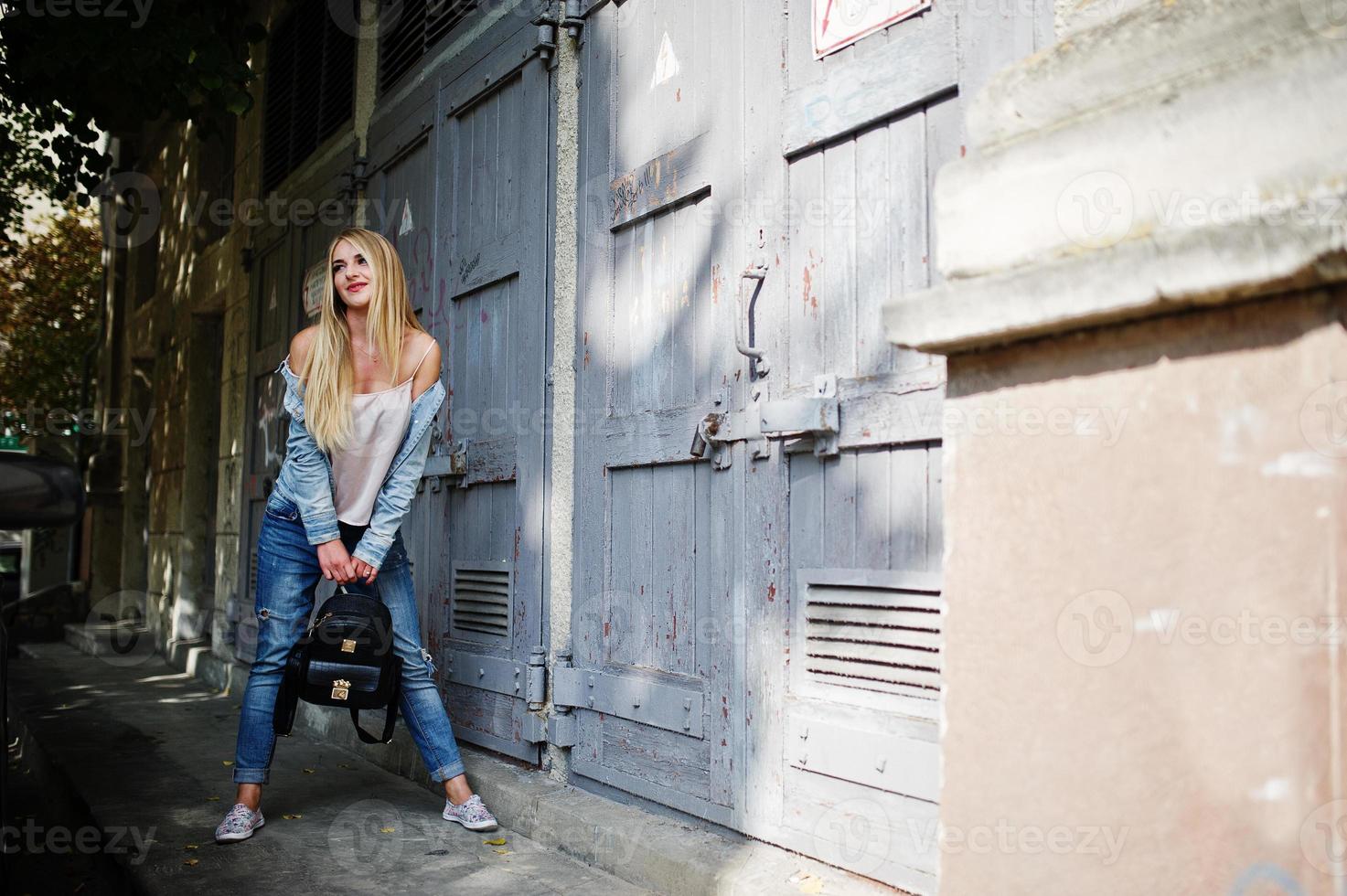 fille blonde porte une veste en jean posée dans la rue. photo