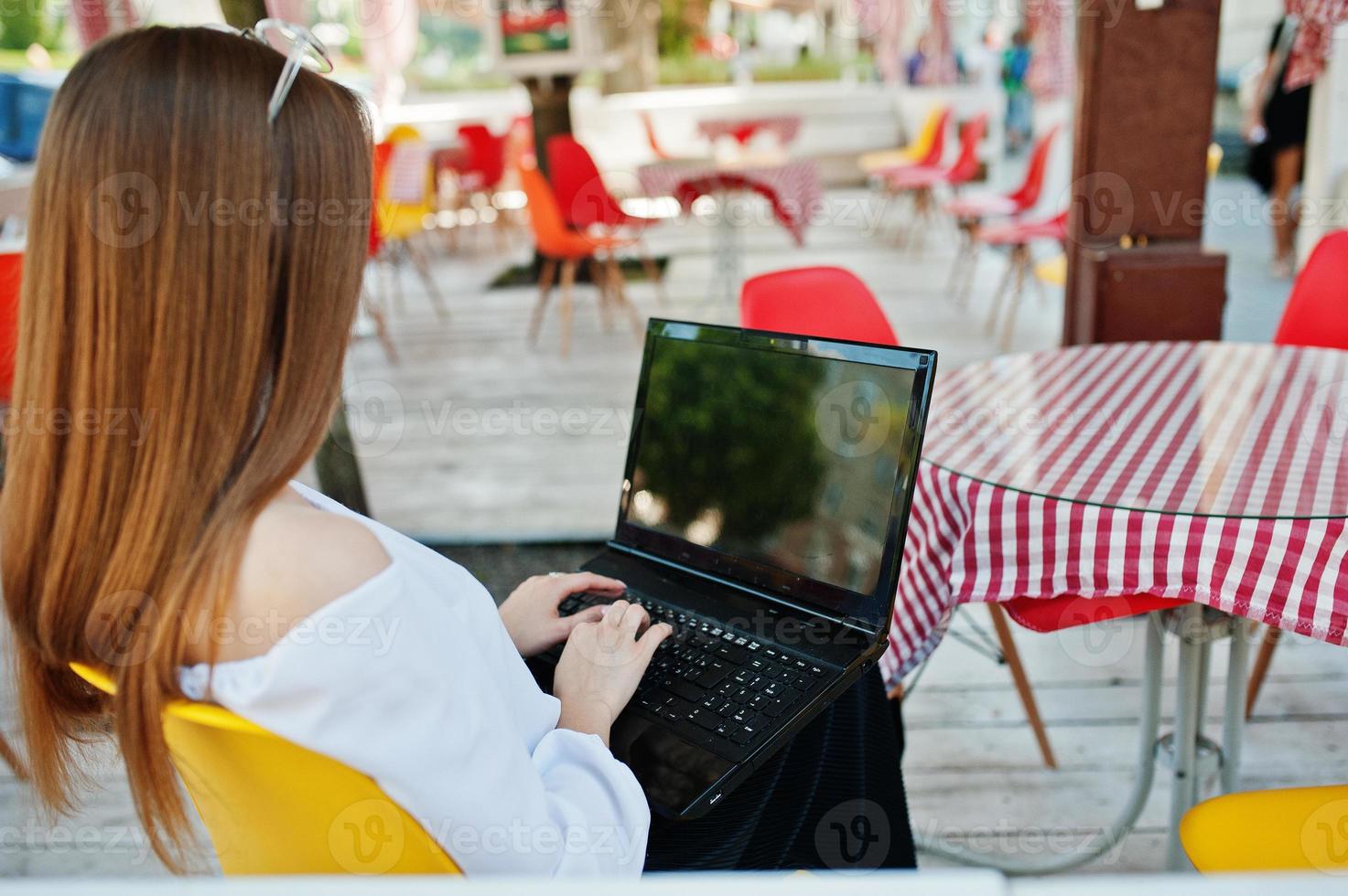 portrait d'une femme d'affaires indépendante forte et prospère portant des vêtements et des lunettes décontractés intelligents travaillant sur un ordinateur portable dans un café. photo