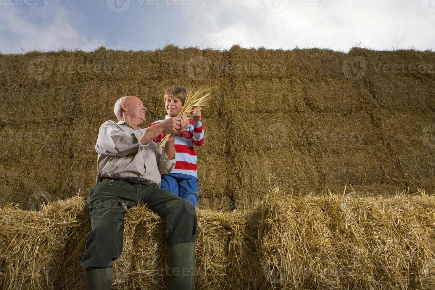 agriculteur et petit-fils assis sur une pile de balles de foin photo