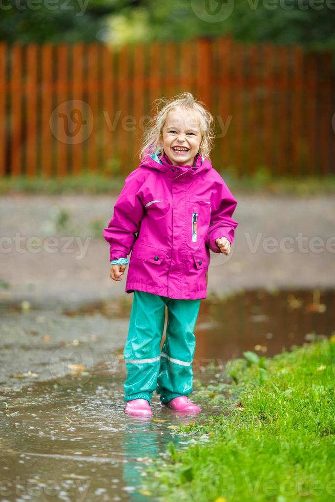 heureuse petite fille joue dans une flaque d'eau photo