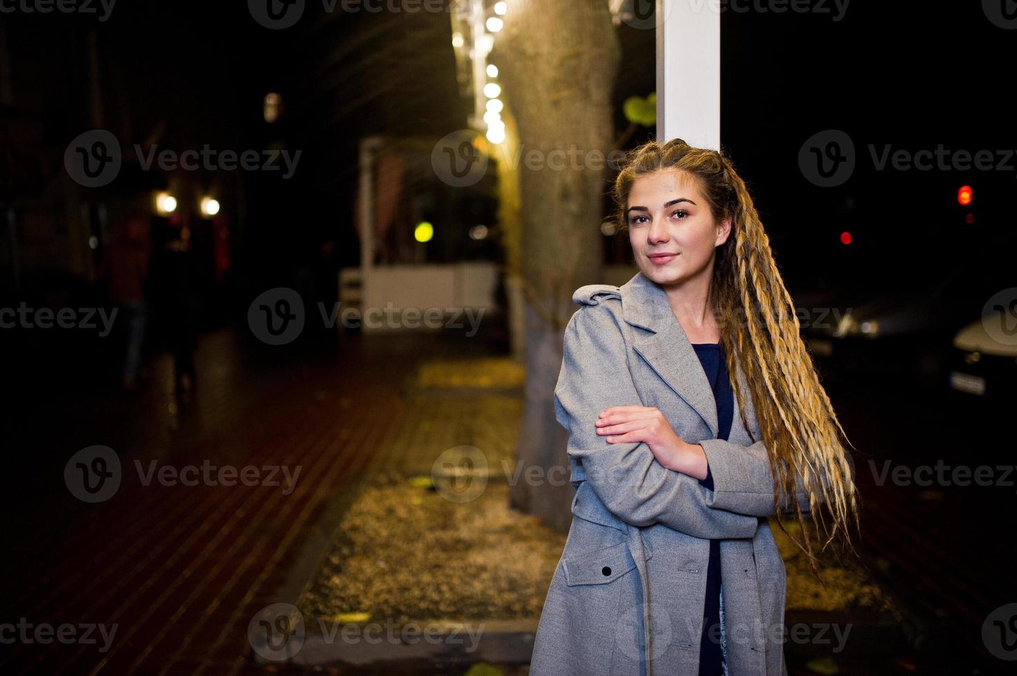 fille avec des dreadlocks marchant dans la rue de nuit de la ville. photo