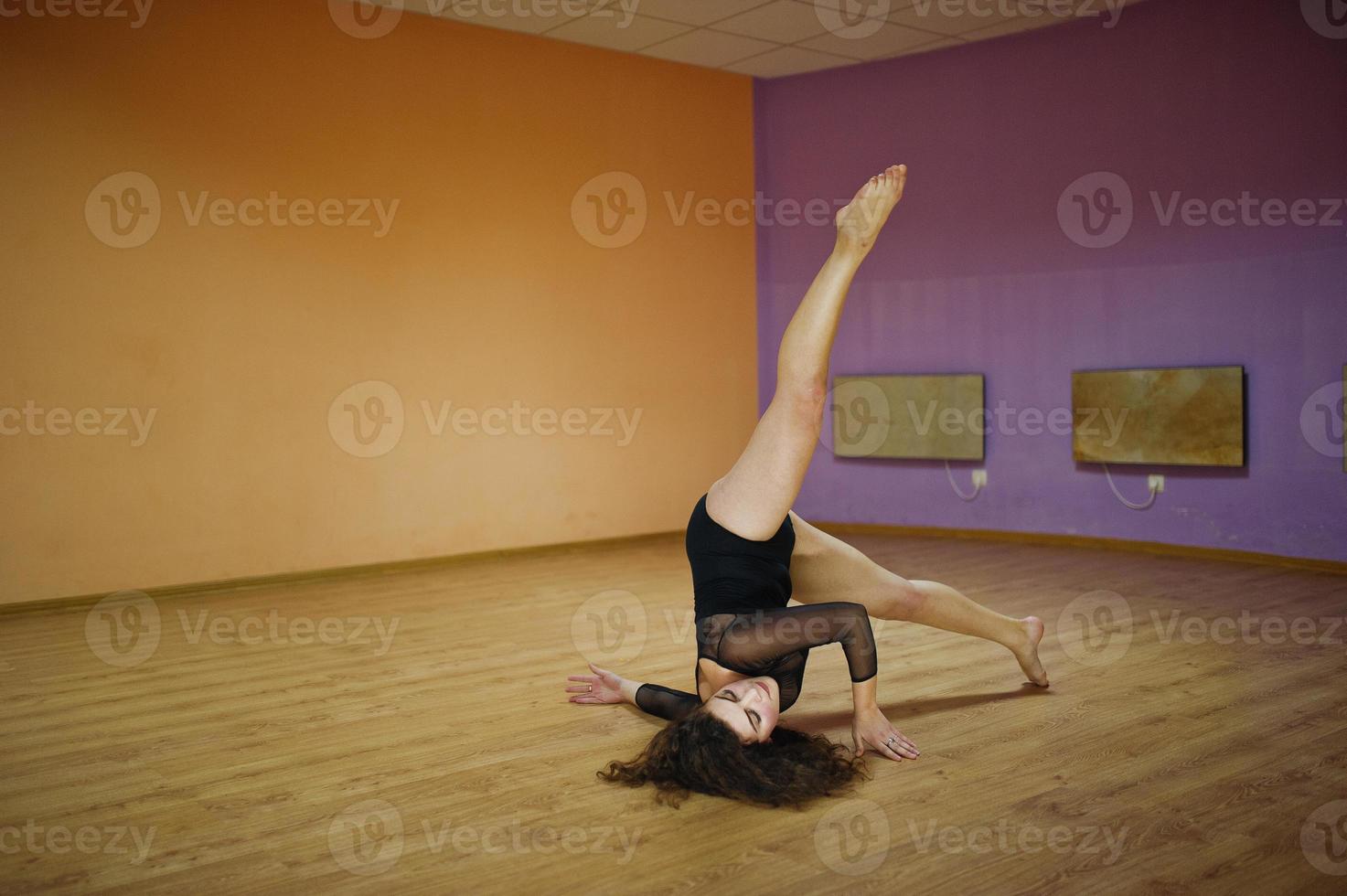 brune frisée plus modèle de taille faisant des acrobaties à la salle de danse. photo