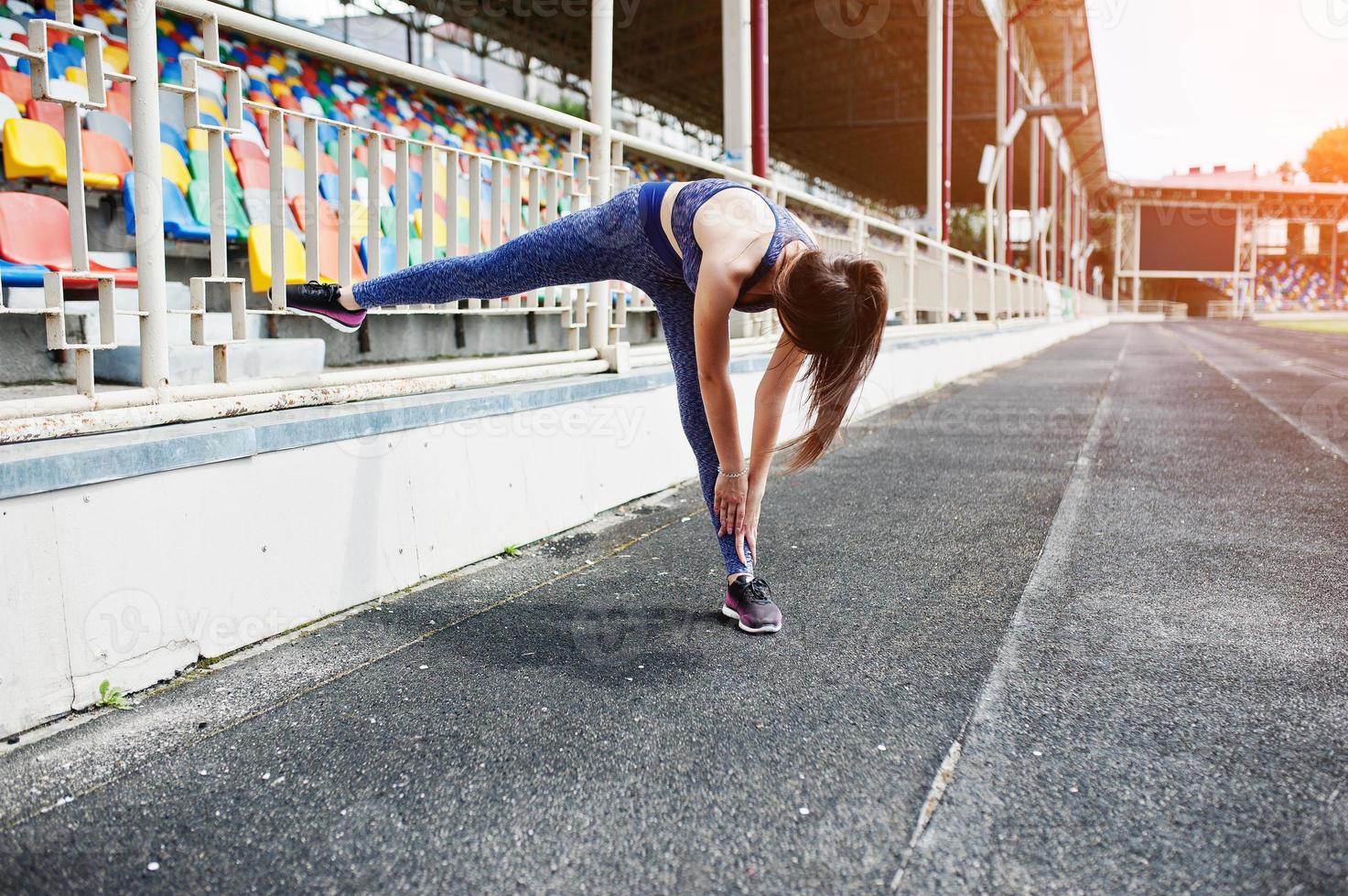 portrait d'une belle femme en tenue de sport étirant ses muscles dans le stade. photo