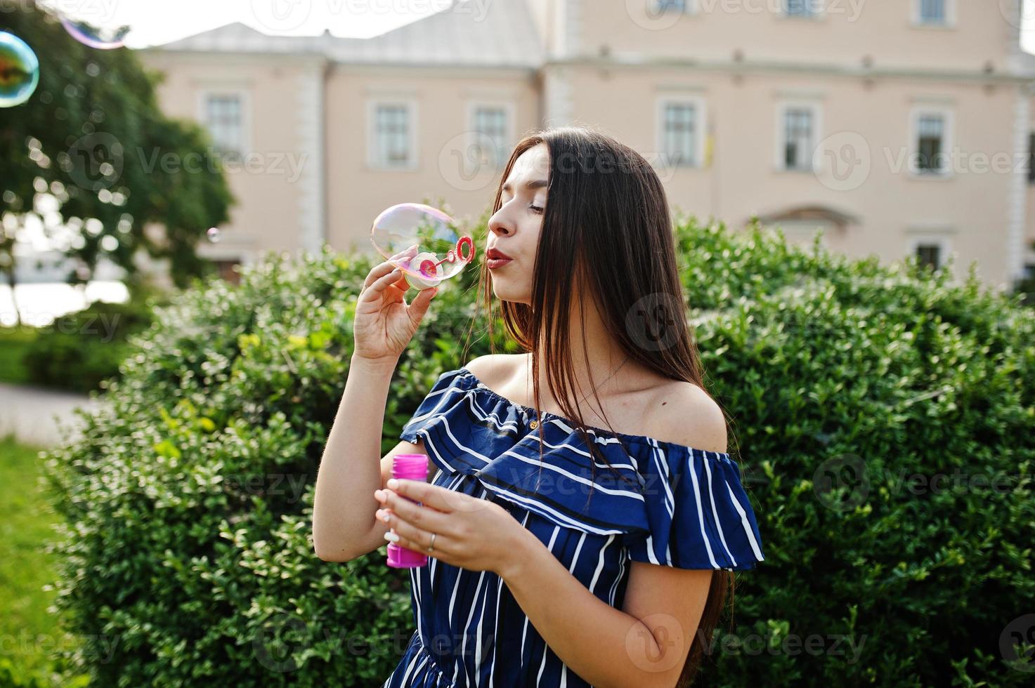 une superbe fille brune dans la rue de la ville laisse échapper des bulles de savon. photo