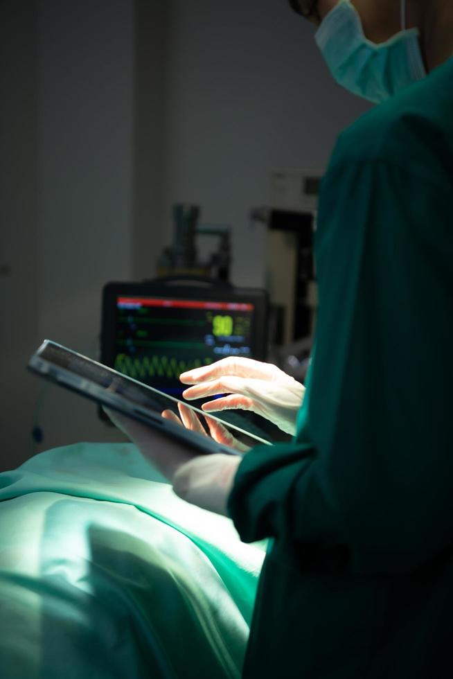 le médecin discute du cas avec une tablette. avant d'aller en chirurgie sur le vrai patient photo