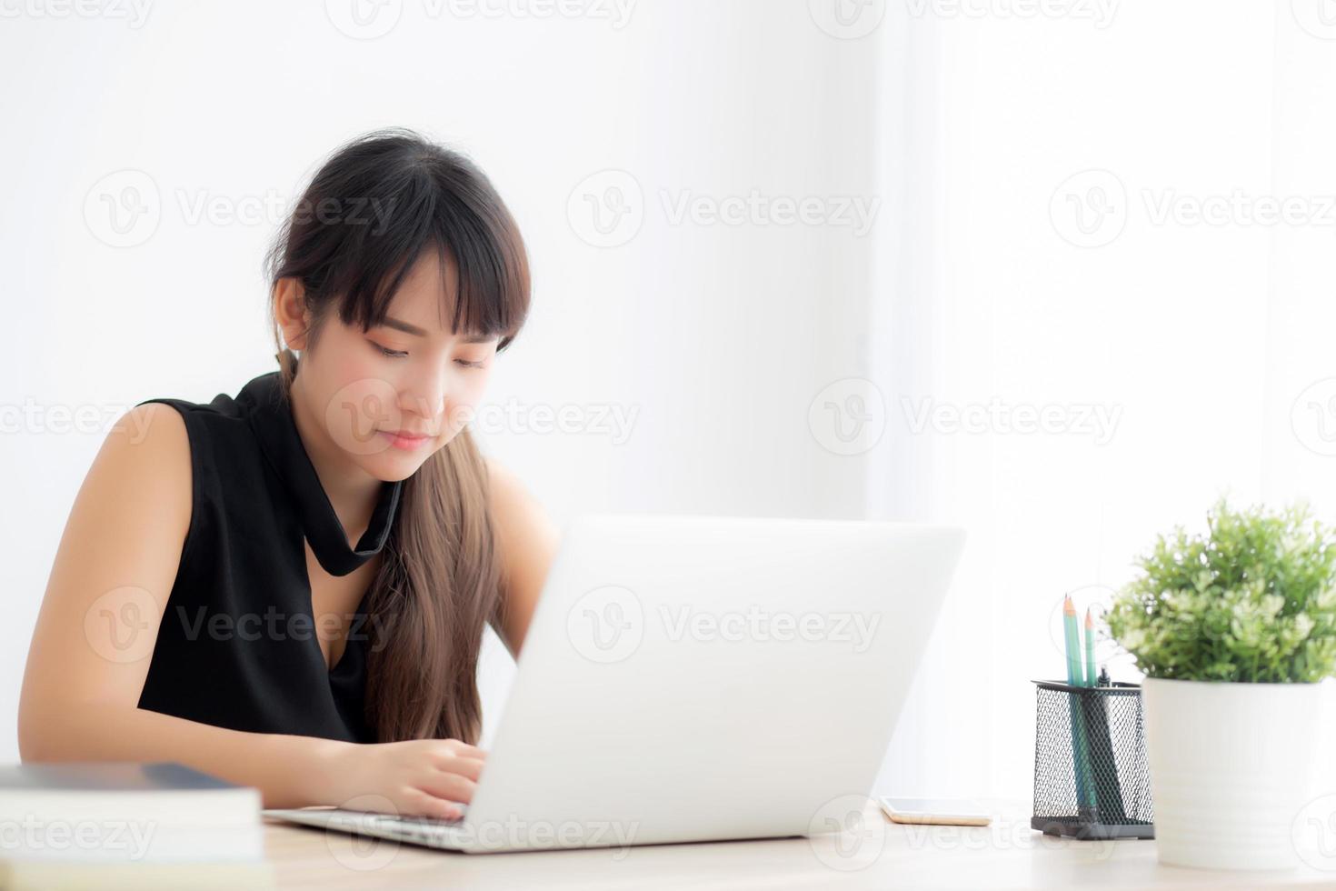 jeune femme asiatique indépendante souriante travaillant et tapant sur un ordinateur portable au bureau avec un professionnel, une fille utilisant un ordinateur portable vérifiant le courrier électronique ou le réseau social, le concept d'entreprise et de style de vie. photo