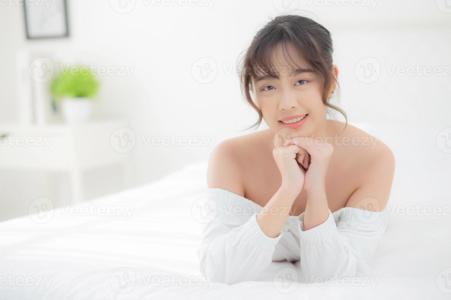 beau portrait jeune femme asiatique allongée et souriante au réveil avec le lever du soleil le matin, beauté jolie fille heureuse et joyeuse reposant sur le lit dans la chambre, mode de vie et concept de détente. photo