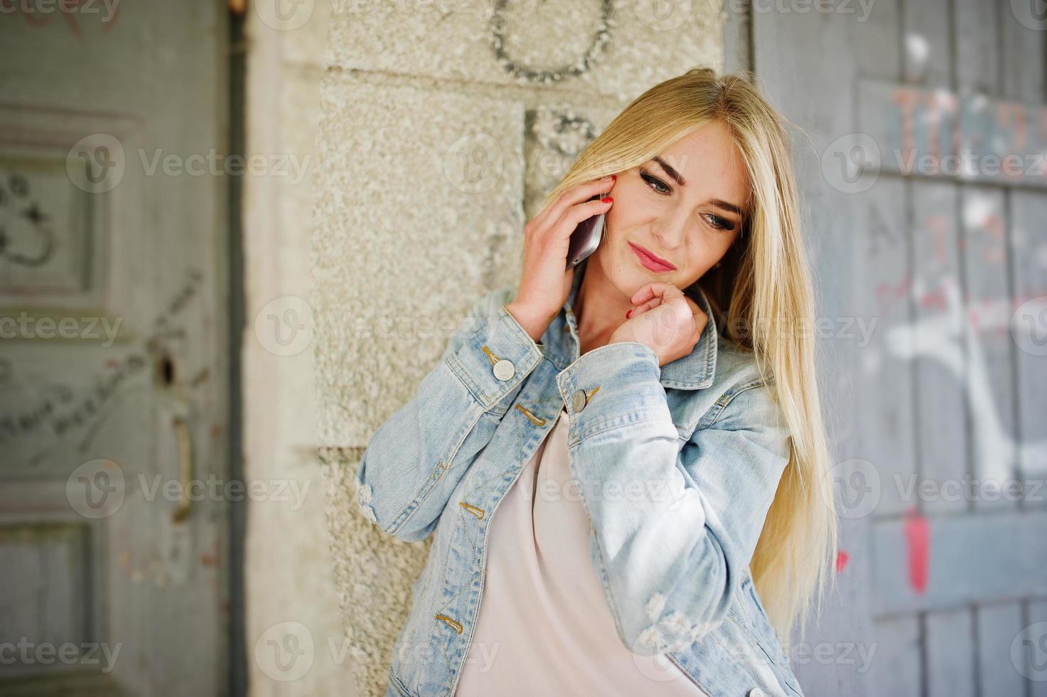 fille blonde porte une veste en jean posée dans la rue. photo