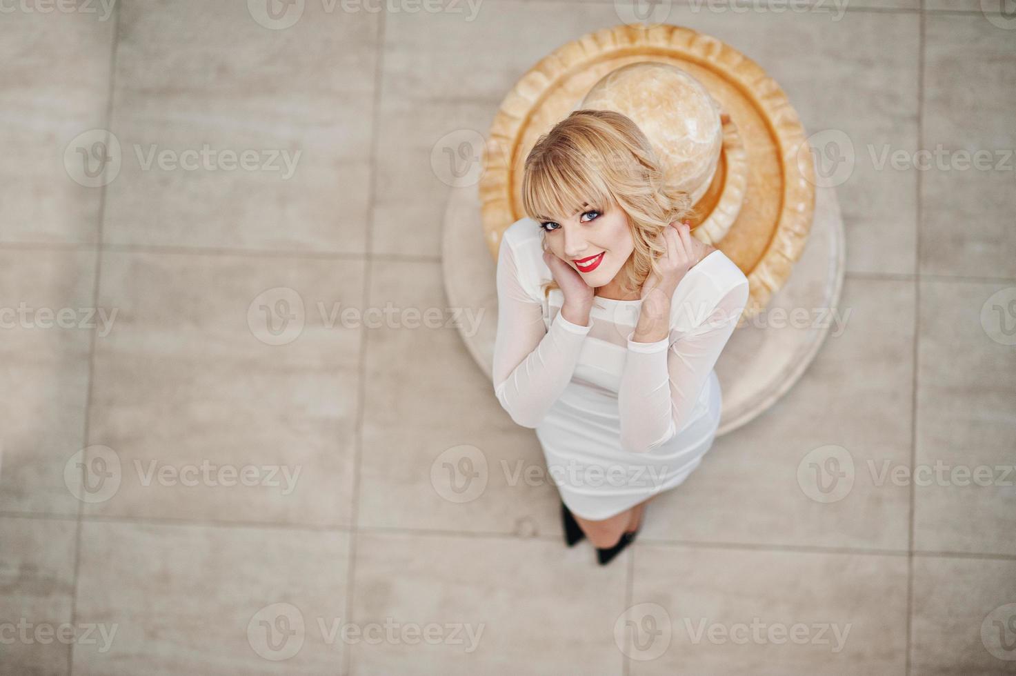 fille blonde en robe blanche posée sur les escaliers blancs du hall. photo