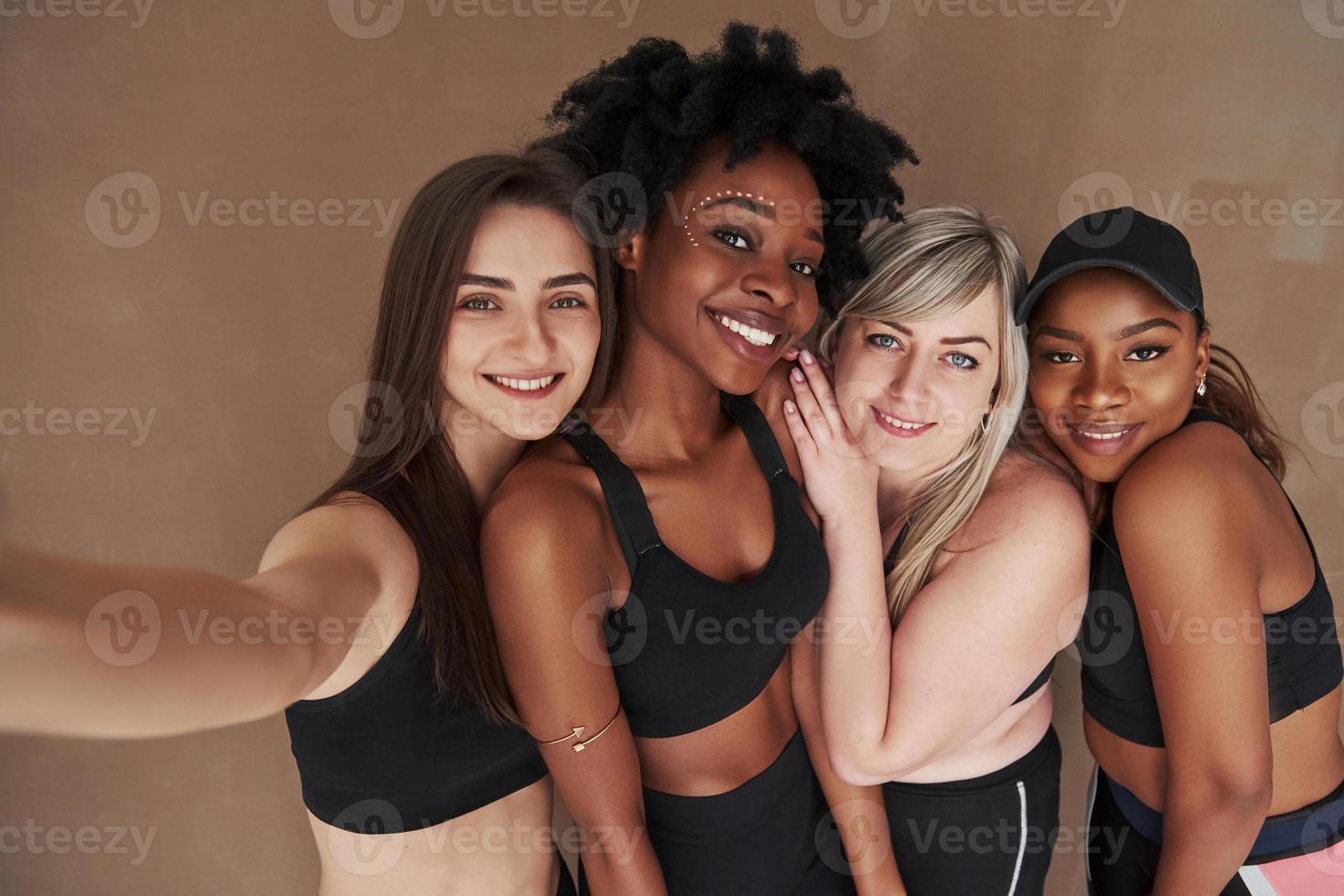 plus besoin de photographe. groupe de femmes multiethniques debout dans le studio sur fond marron photo