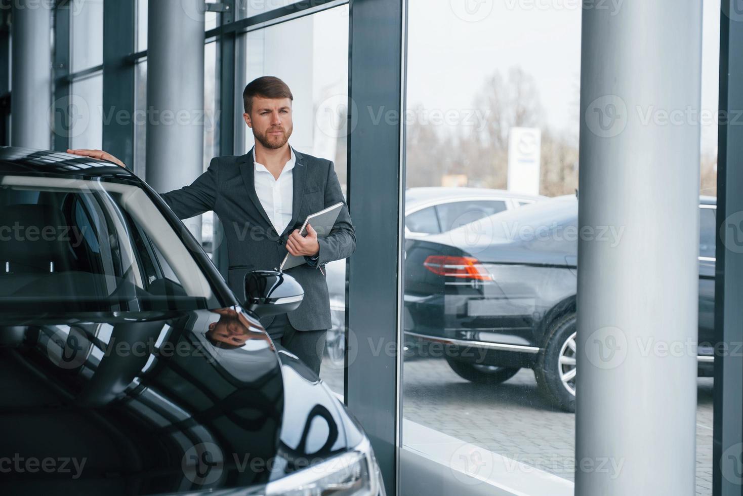 regarde de loin. homme d'affaires barbu élégant et moderne dans le salon automobile photo