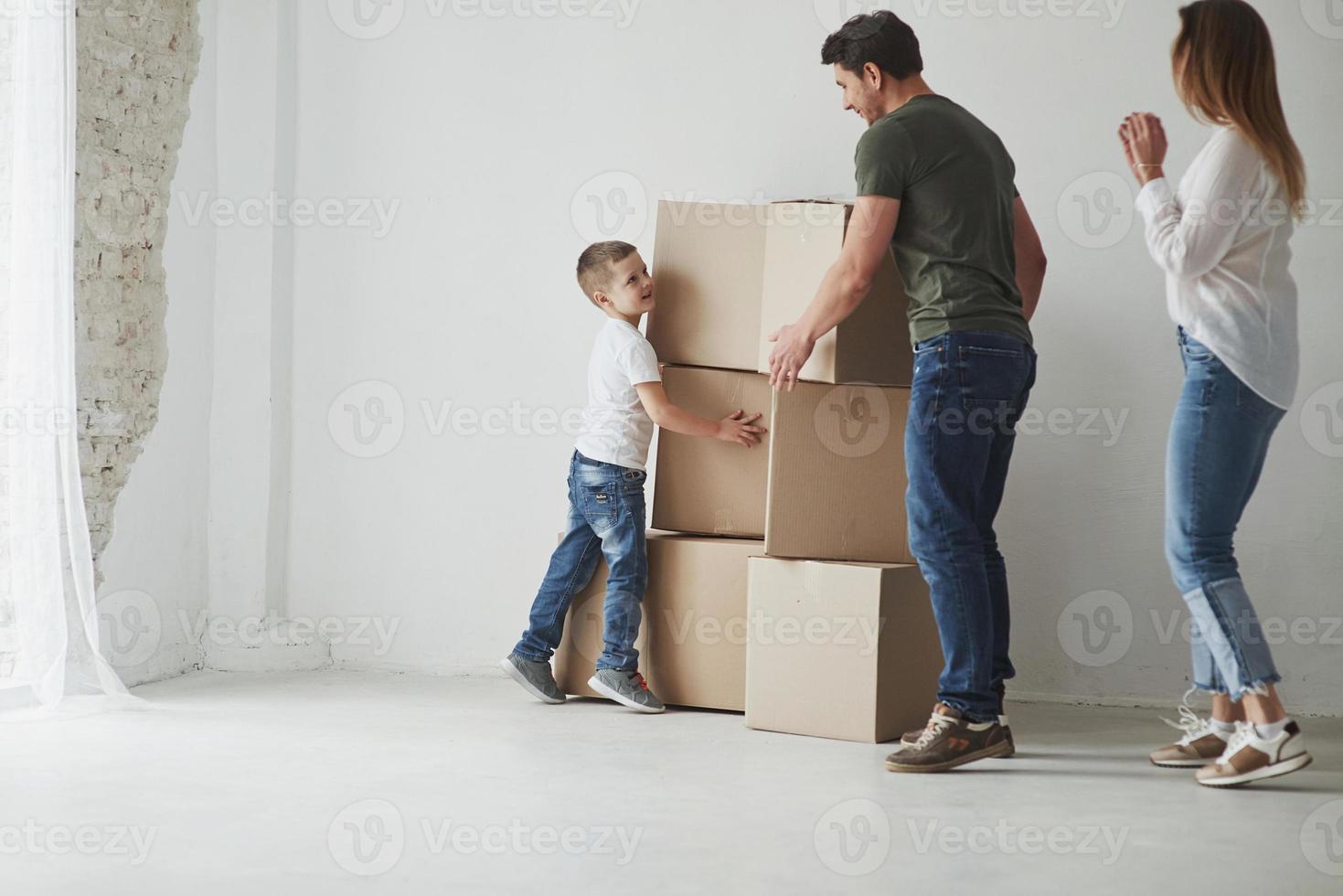 petite aide. la famille a été transférée dans une nouvelle maison. déballage des cartons de déménagement photo