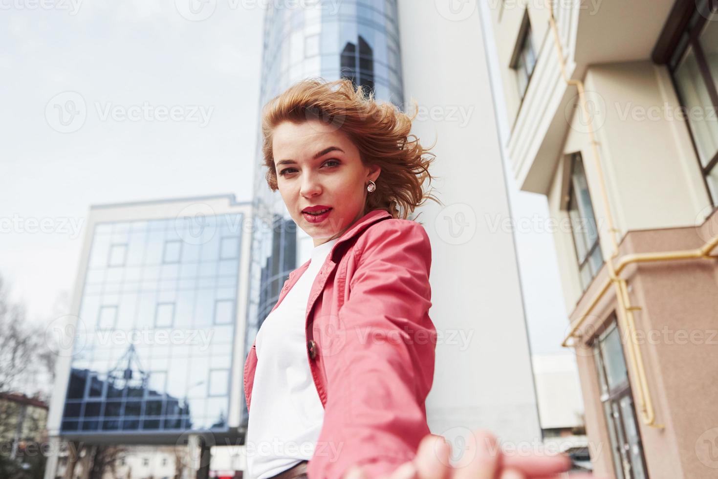 vue de face. jolie femme adulte en manteau rouge chaud se promener dans la ville le week-end photo