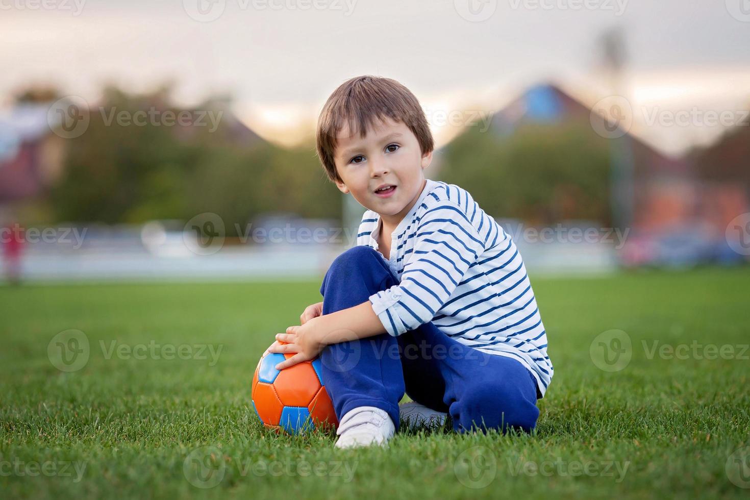 petit garçon enfant jouant au football et au football, s'amuser surpasser photo