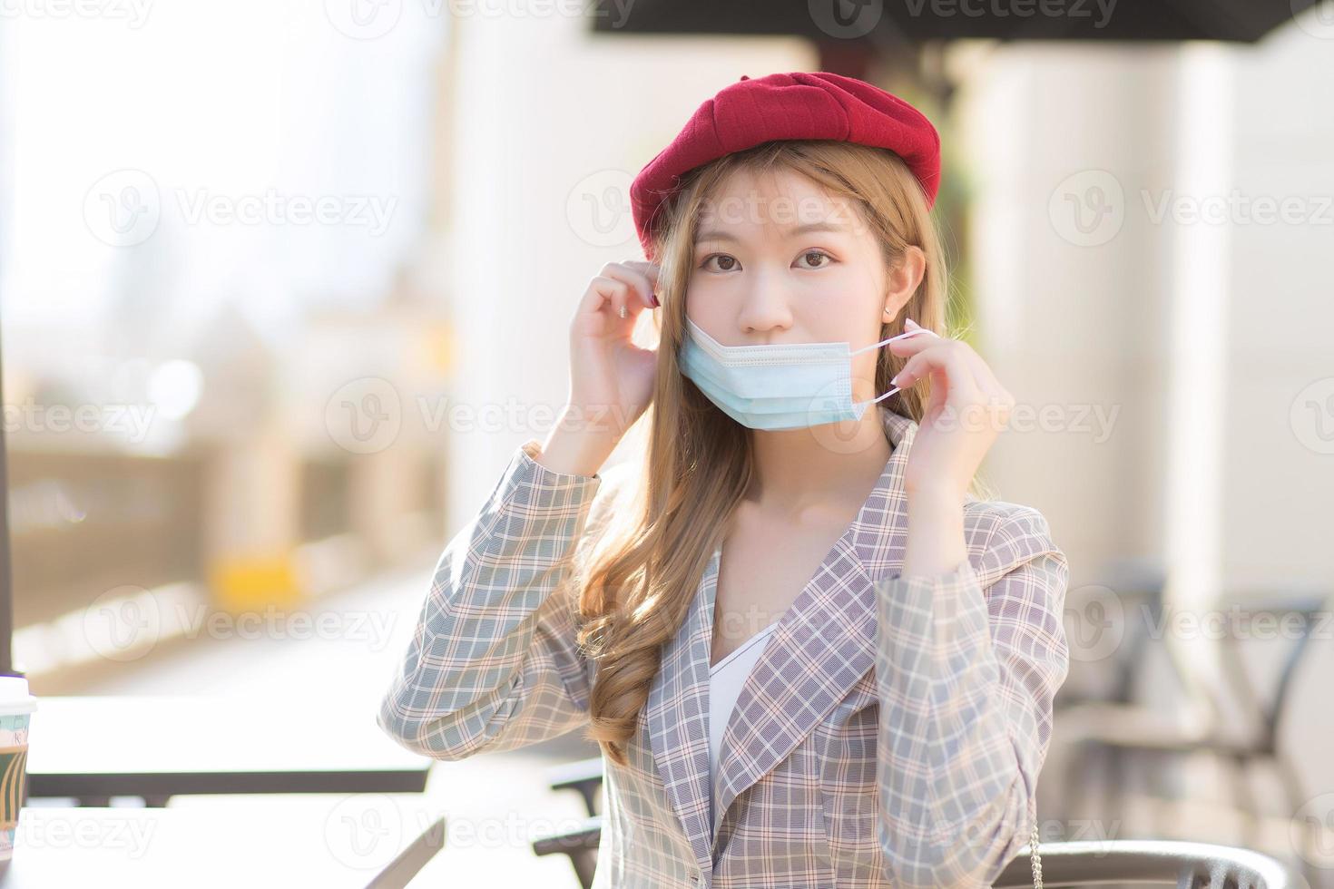 une femme asiatique qui porte un costume et une casquette rouge porte un masque médical dans un nouveau style normal et un concept de soins de santé. photo