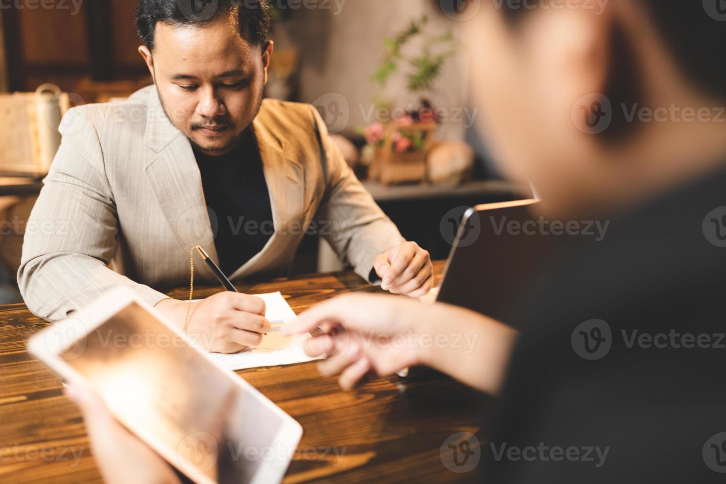 jeune homme d'affaires asiatique travaillant sur des documents papier dans un bureau moderne, un homme professionnel est heureux de démarrer une entreprise avec une nouvelle personne travaillant en équipe en utilisant un plan d'affaires pour travailler photo