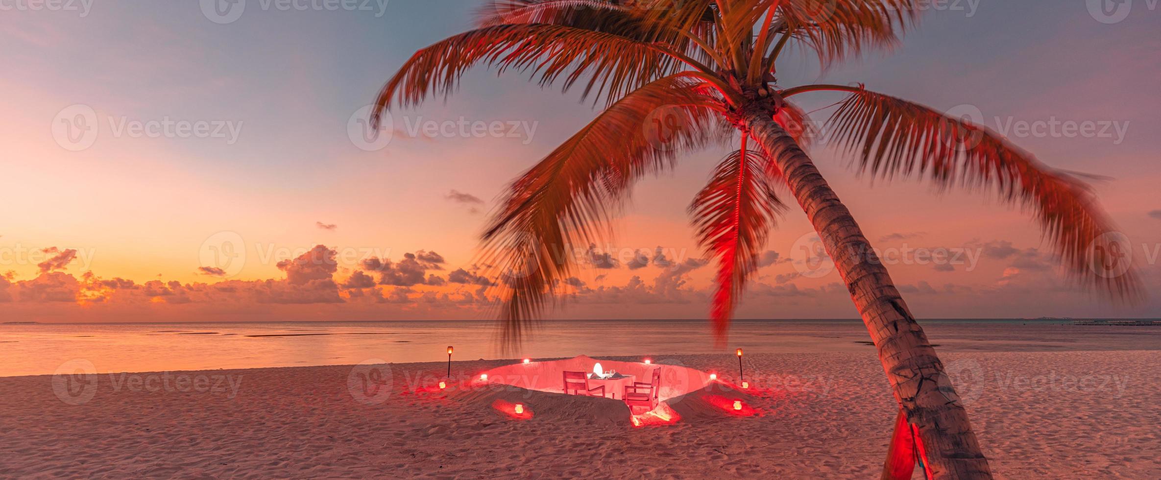 dîner romantique sur la plage avec coucher de soleil, bougies aux feuilles de palmier et ciel et mer au coucher du soleil. vue imprenable, paysage de lune de miel ou de dîner d'anniversaire. horizon de soirée île exotique, romance pour un couple photo