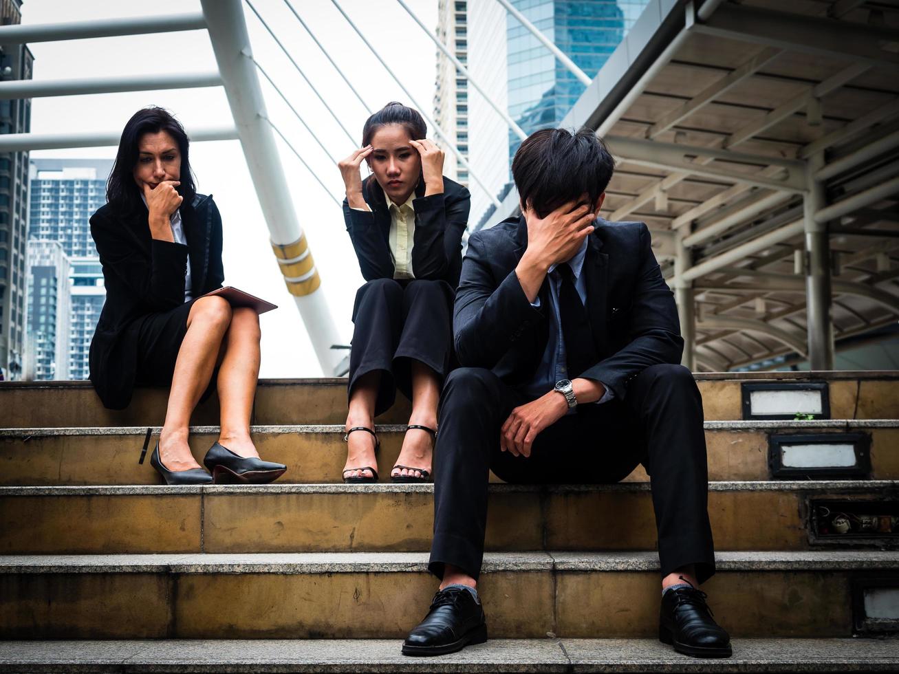 groupe d'hommes et de femmes d'affaires assis dans un parc extérieur et stressés à cause de l'échec du travail dans l'entreprise photo