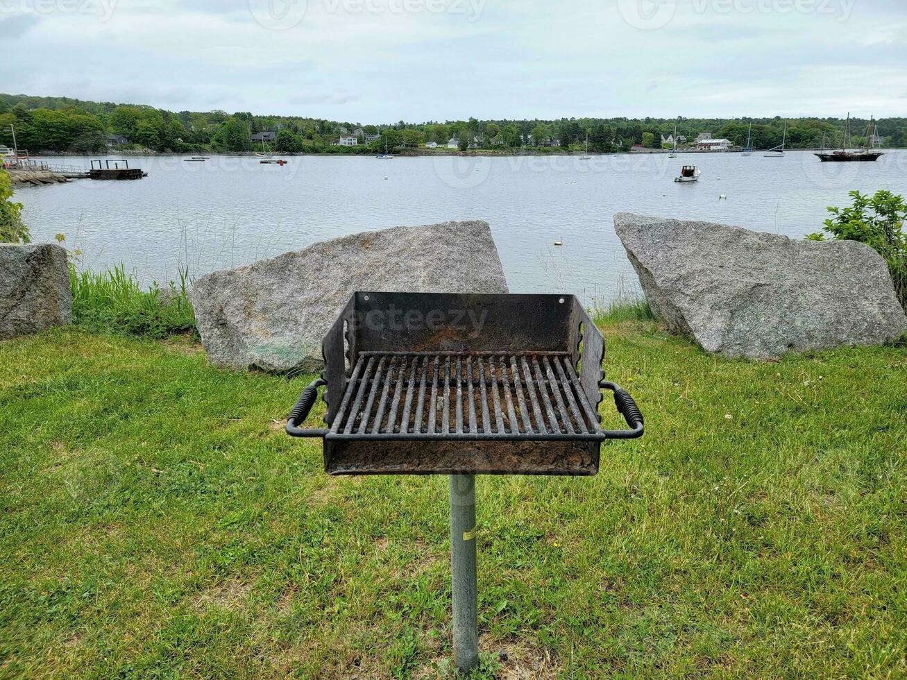 barbecue dans l'herbe près du lac avec des bateaux et des rochers photo