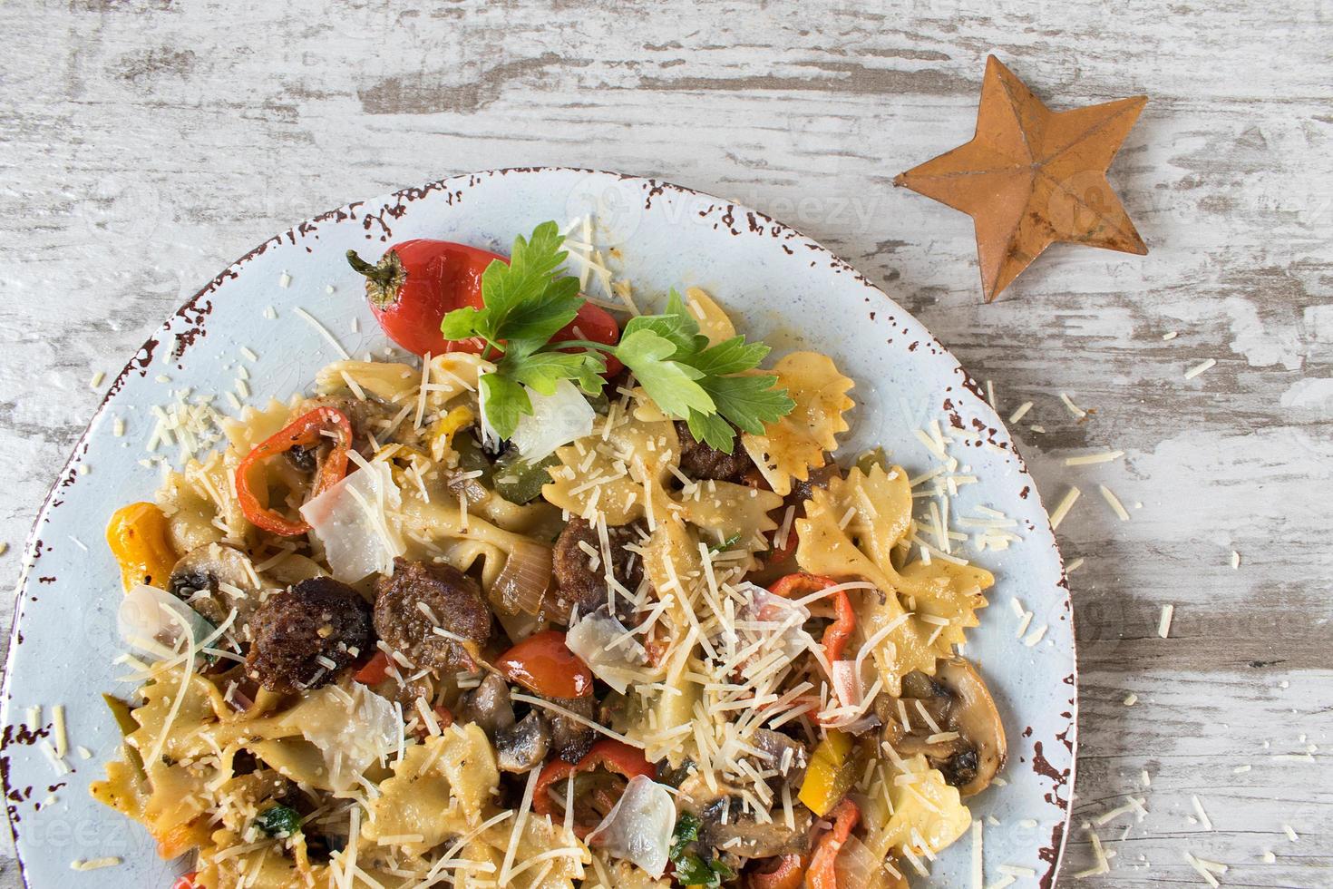 pâtes papillon aux tomates et champignons saupoudrés de fromage et d'herbes photo