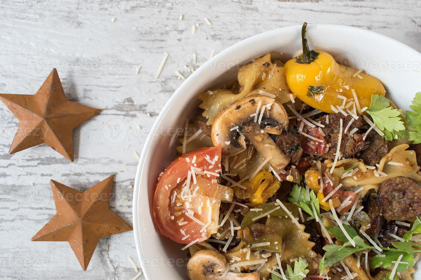 pâtes papillon aux tomates et champignons saupoudrés de fromage et d'herbes photo