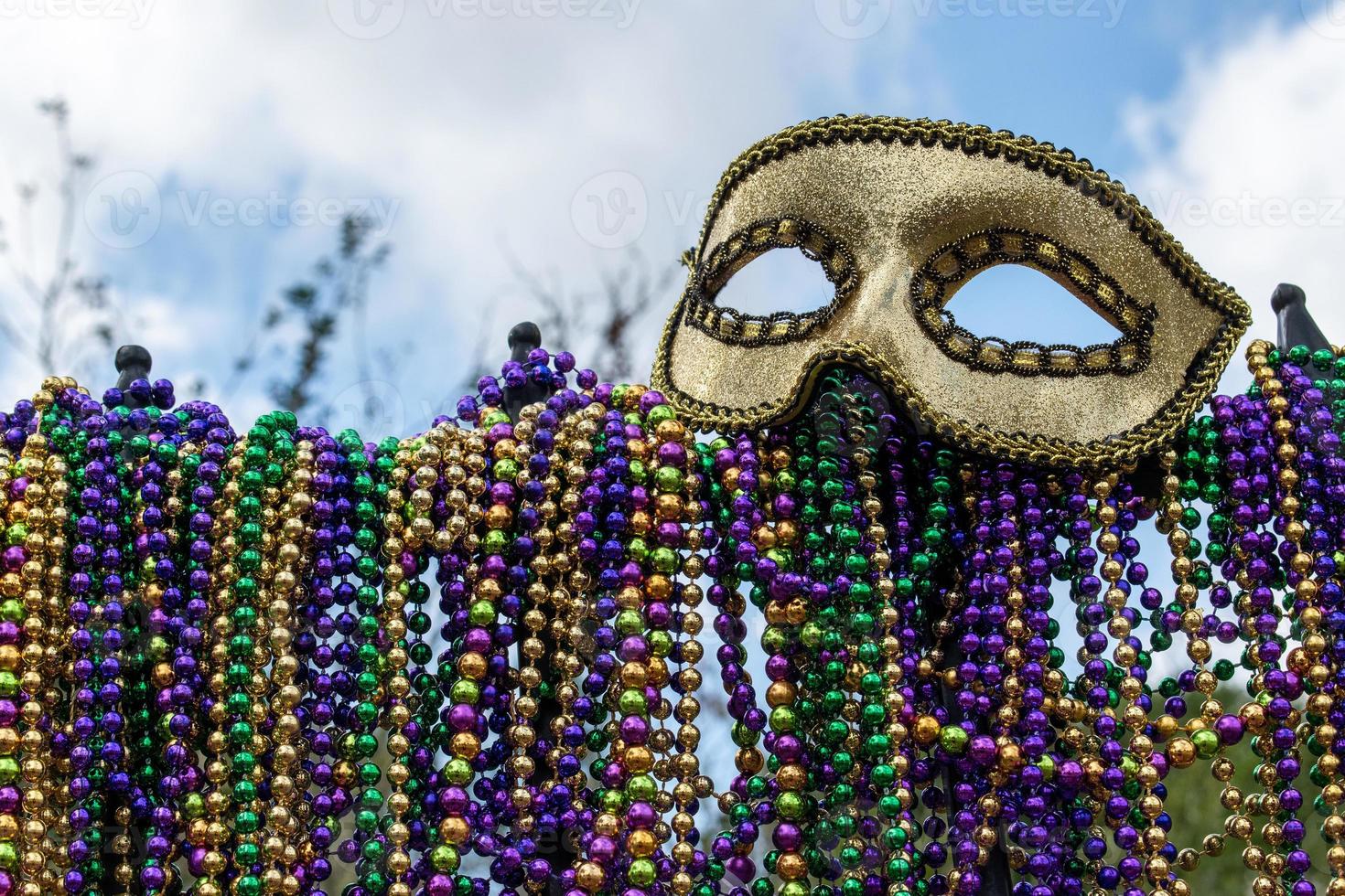 clôture en fer recouverte de perles de mardi gras surmontée d'un masque photo