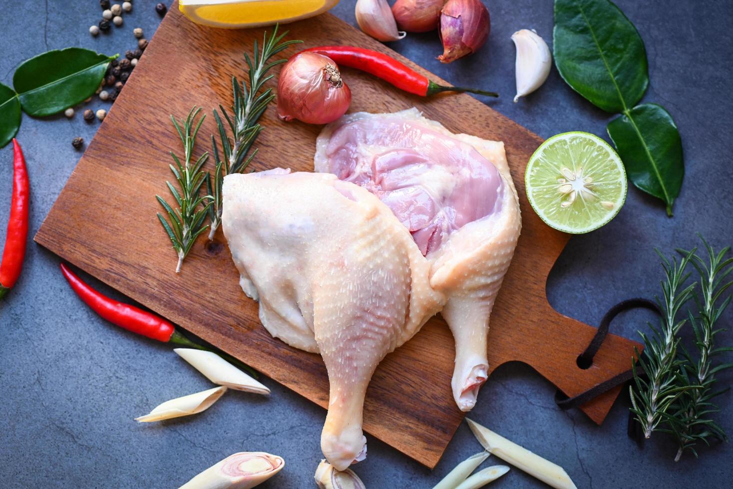 cuisses de canard crues aux épices aux herbes prêtes à cuire sur une planche à découper en bois, viande de canard fraîche pour la nourriture photo