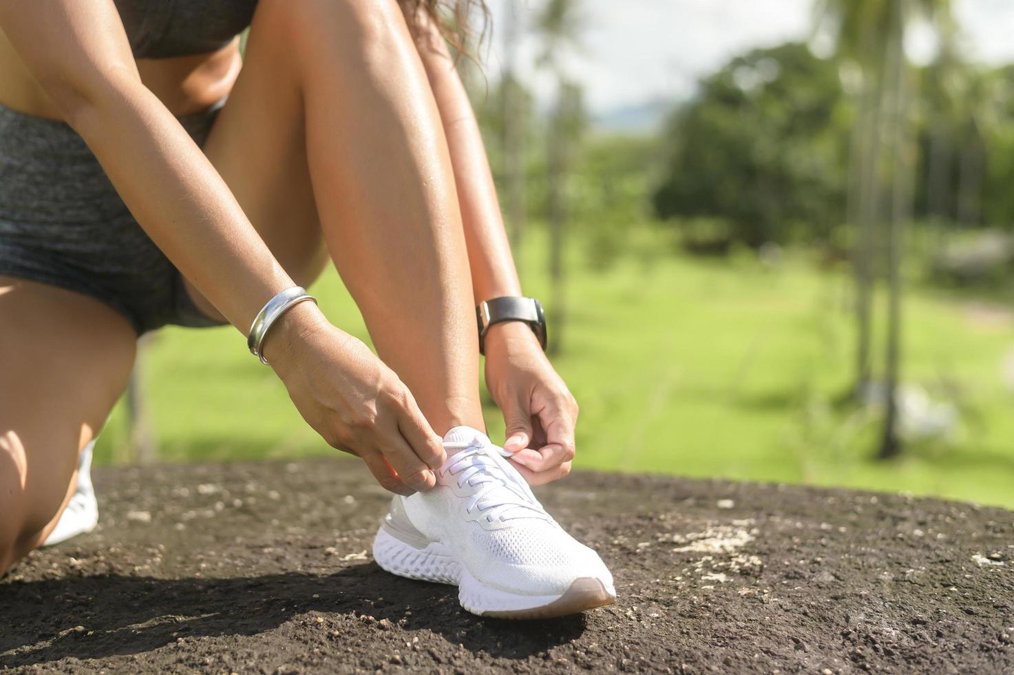 belle femme en forme de vêtements de sport attachant des lacets de chaussures préparez-vous pour l'exercice, la santé et le concept de sport. photo