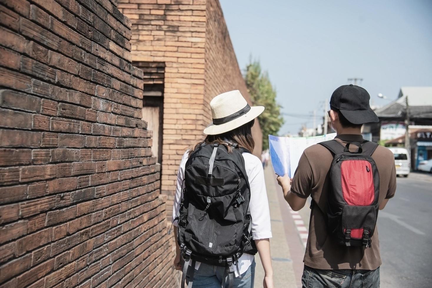 Sac à dos asiatique couple touriste tenant le plan de la ville traversant la route - concept de mode de vie vacances voyage personnes photo