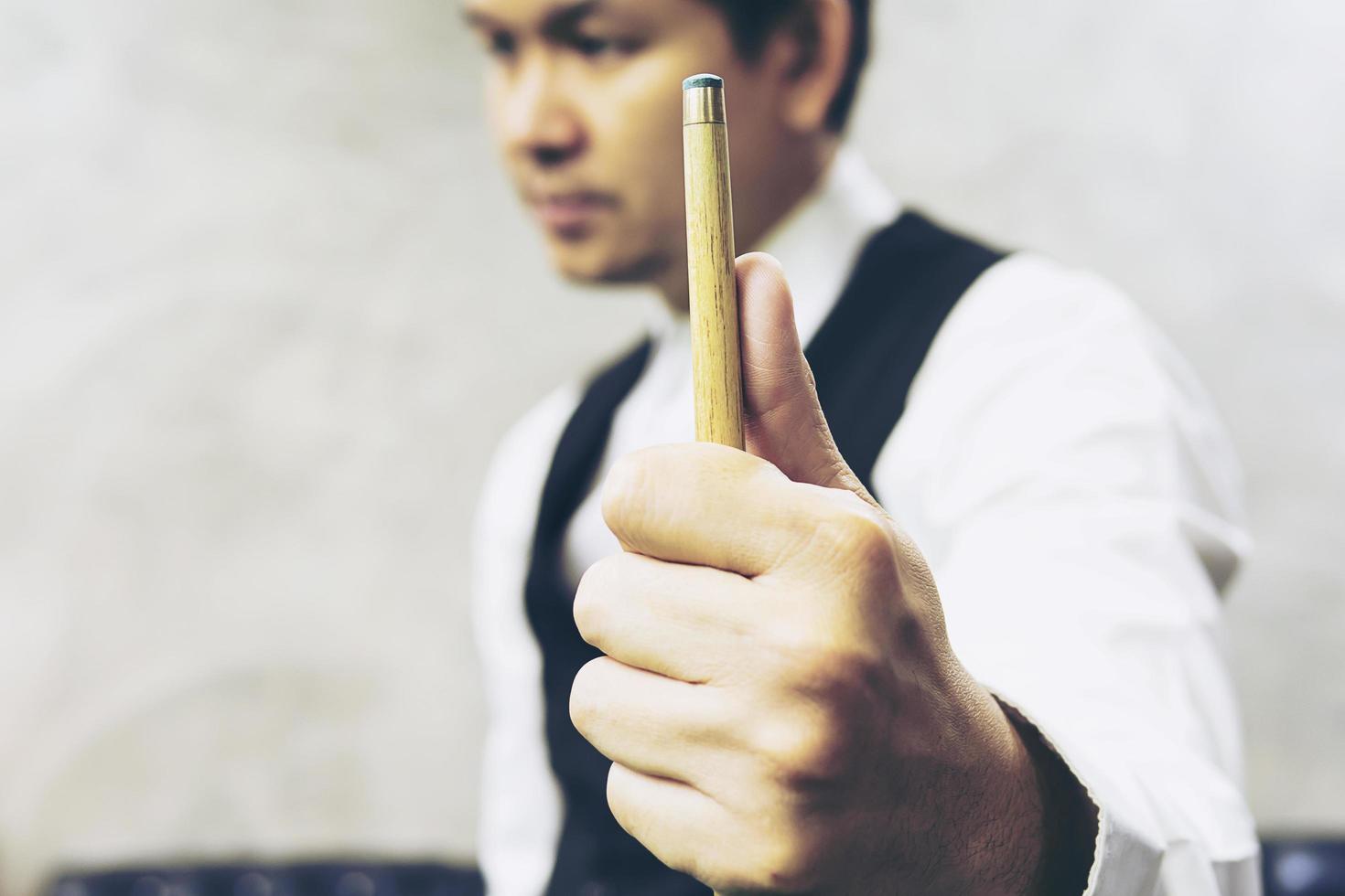 joueur de snooker debout tenir son bâton de repère se préparer à son tour pendant le match de compétition photo