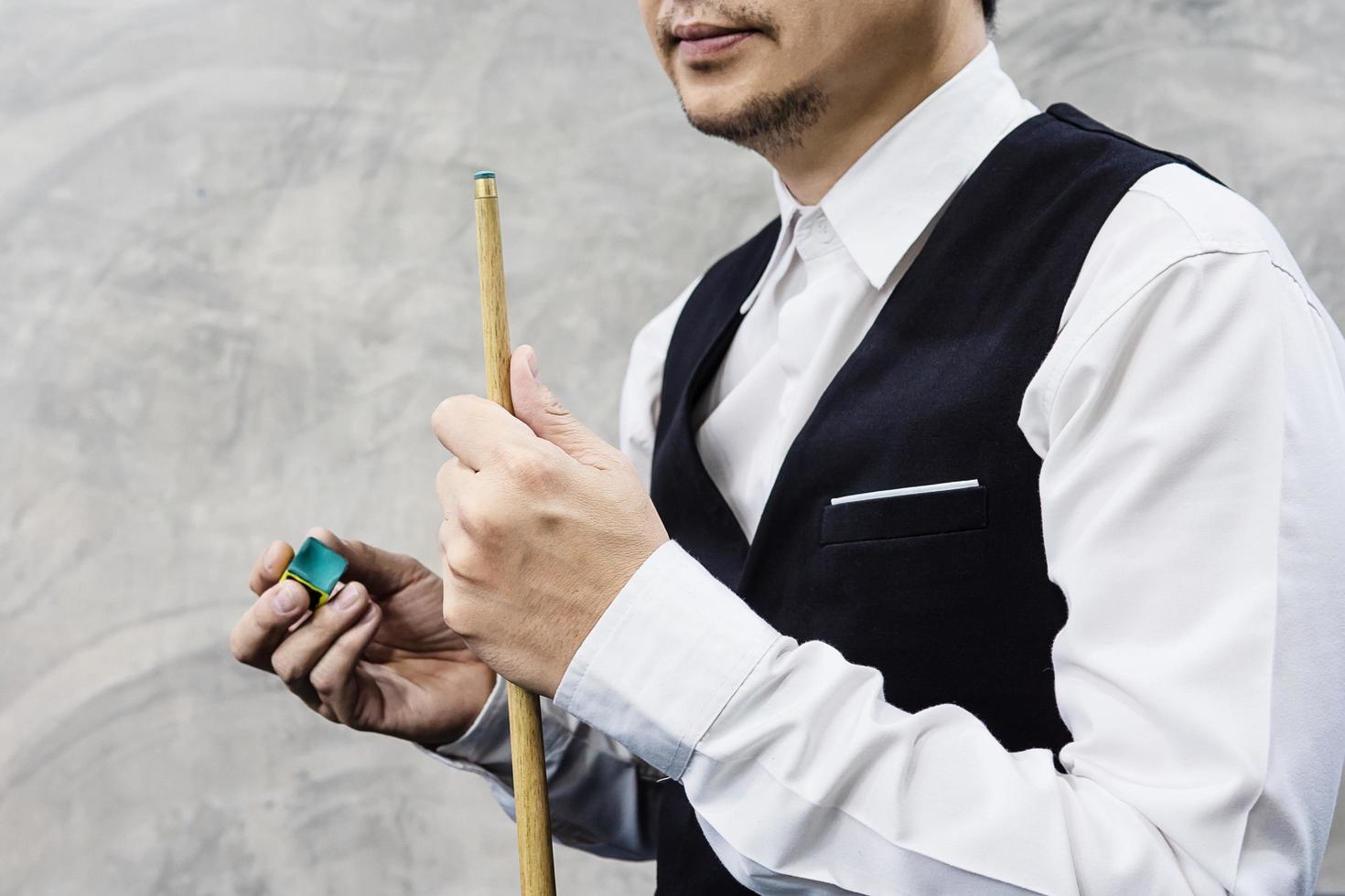joueur de snooker debout attendant tenir son bâton de queue et sa craie se préparer pour son tour pendant le match de compétition photo