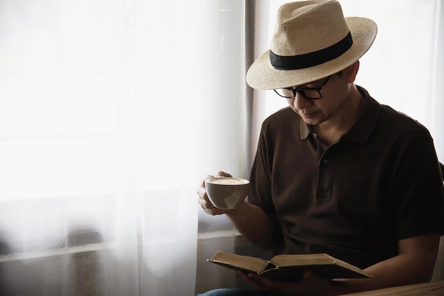 Détendez-vous un homme asiatique buvez du café et lisez un livre dans un café de style moderne - les gens avec une tasse de café concept de style de vie facile photo