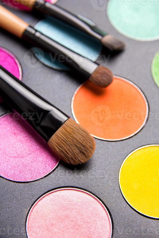 pinceaux de maquillage et palette de fards à paupières colorés sur fond noir close photo
