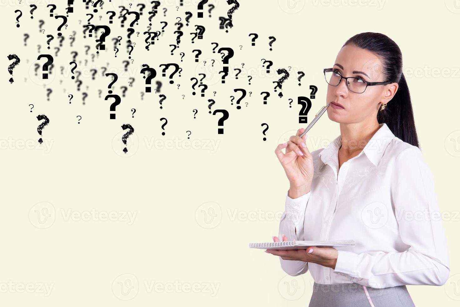 femme d'affaires réfléchie dans des verres sur fond de mur avec des points d'interrogation. concept de décision et de doute. espace de copie. photo