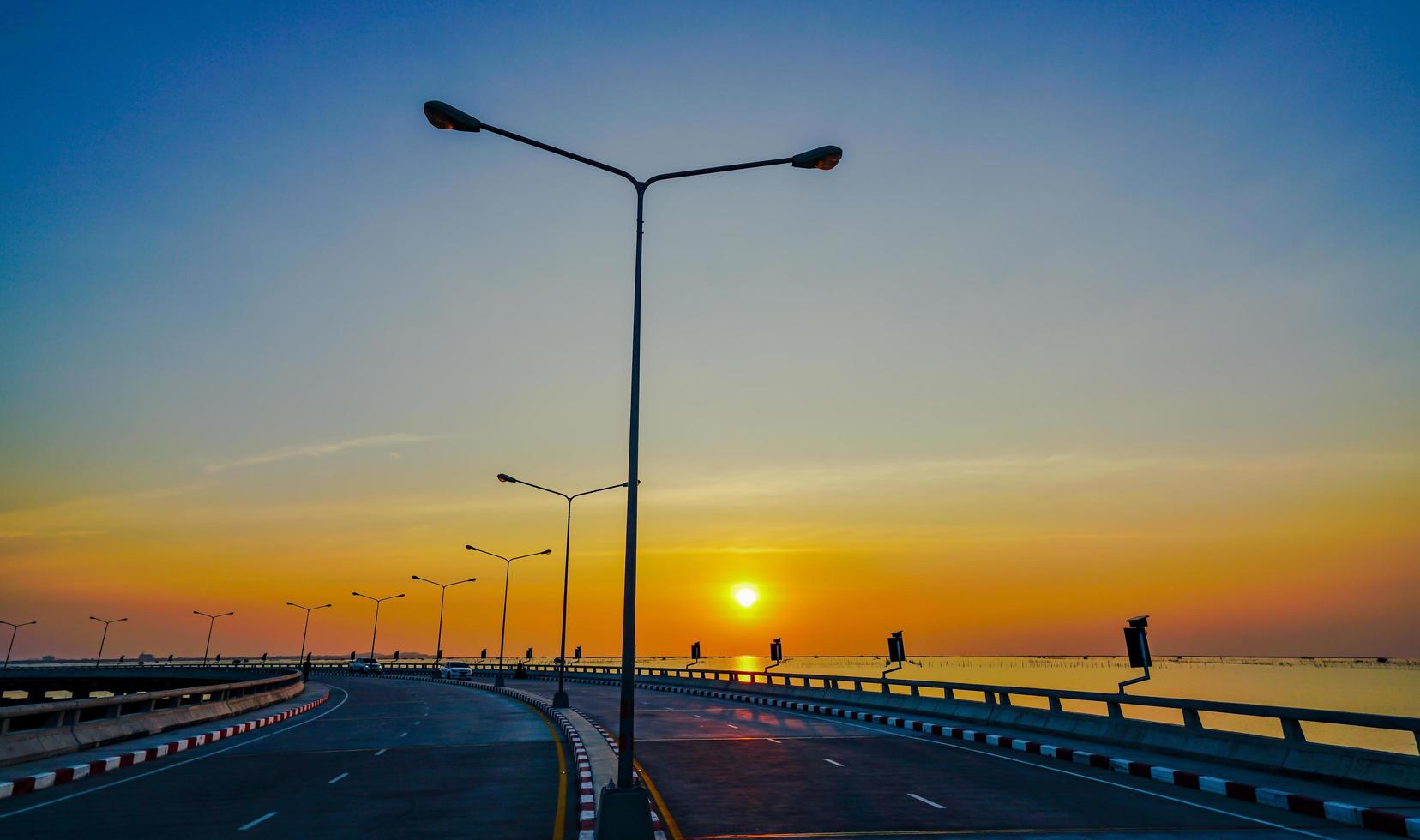 route côtière incurvée avec réverbère et ciel orange au coucher du soleil à chonburi, thaïlande. photo