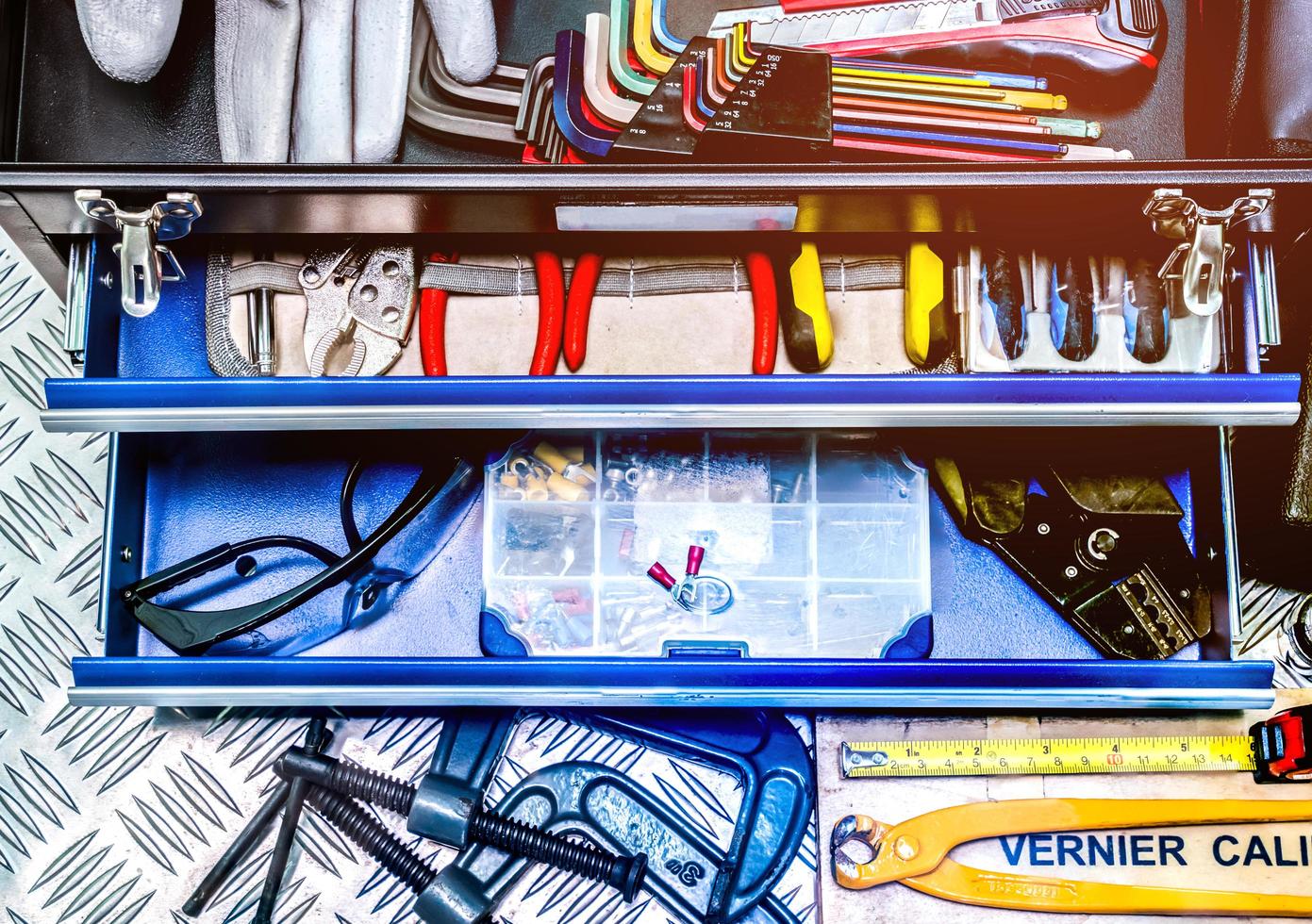 gros plan d'outils en boîte sur fond de plaque à carreaux en atelier. ensemble d'outils de service. construction de maisons et outils électriques. outils à main de plombier. équipement de technicien pour les travaux de réparation. photo