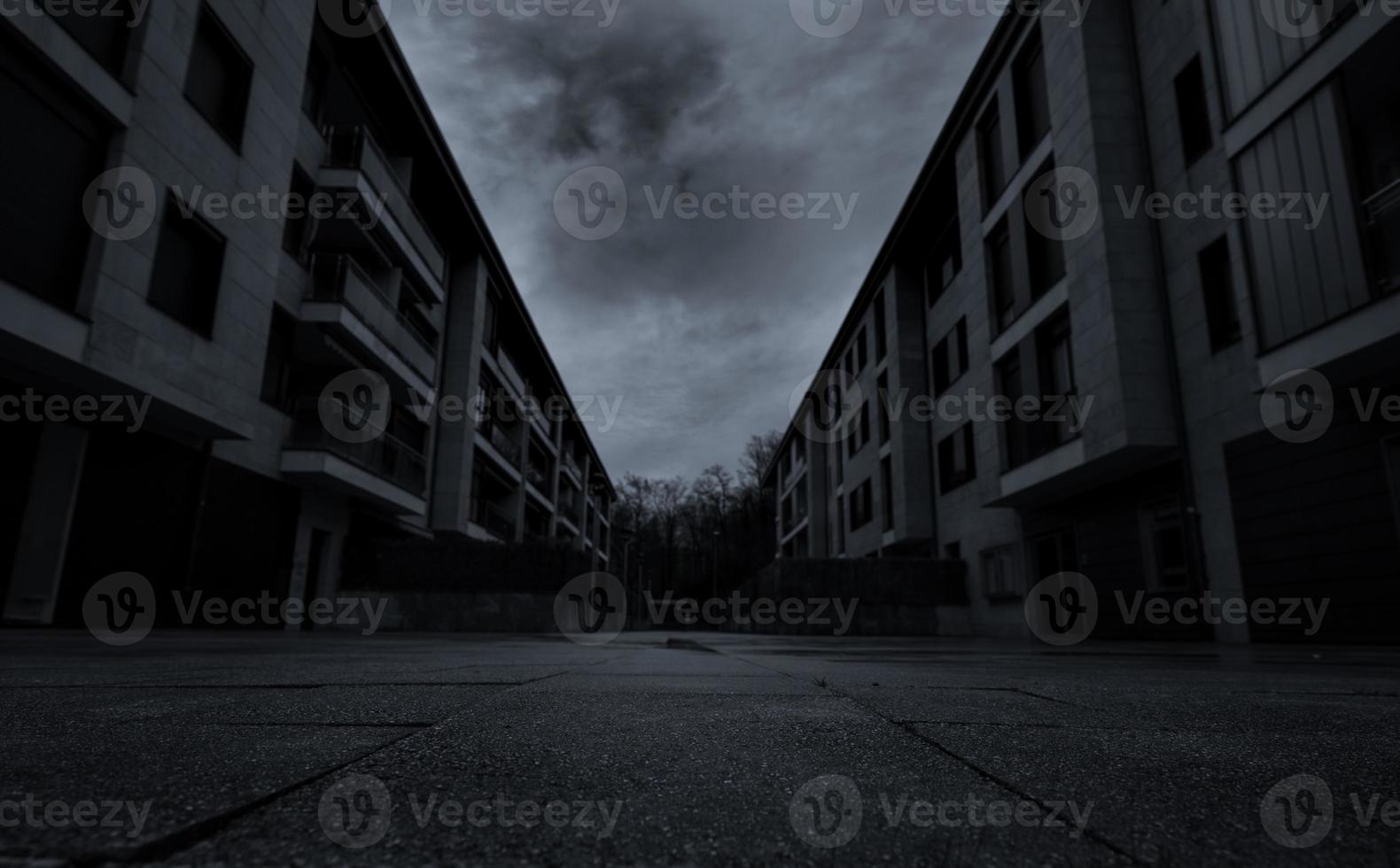 vue en perspective d'une route vide entre un immeuble résidentiel avec des nuages sombres et le ciel de la ville. pas de gens dans la rue urbaine. impact de la crise immobilière et immobilière du coronavirus ou du concept covid-19. photo