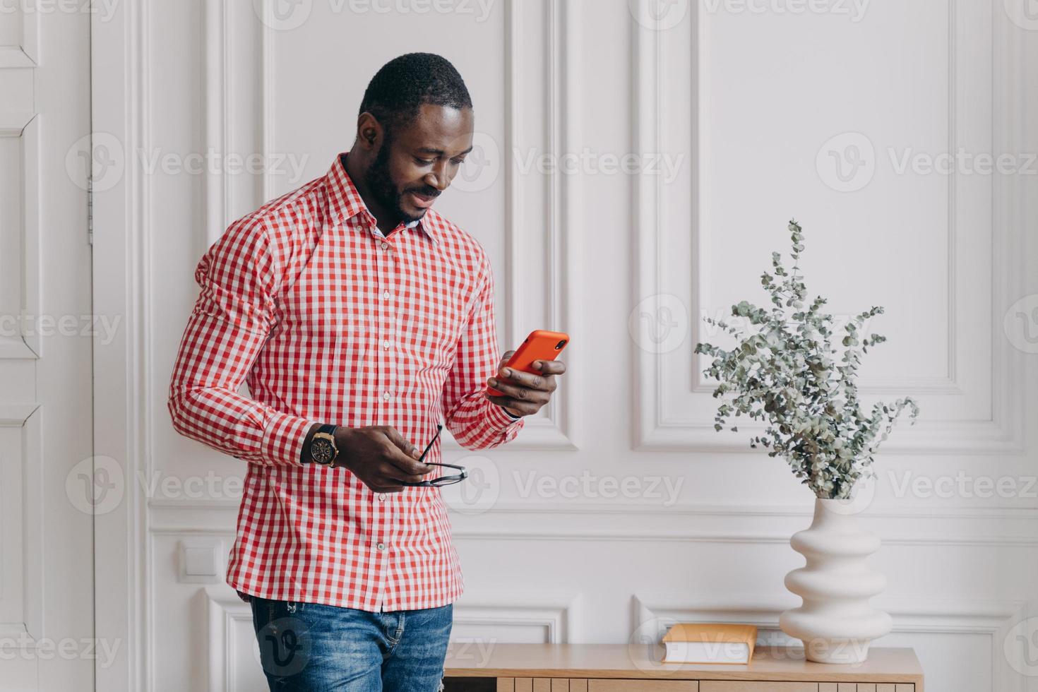 homme d'affaires afro-américain attrayant en vêtements décontractés tenant un smartphone essayant de répondre à un appel important photo